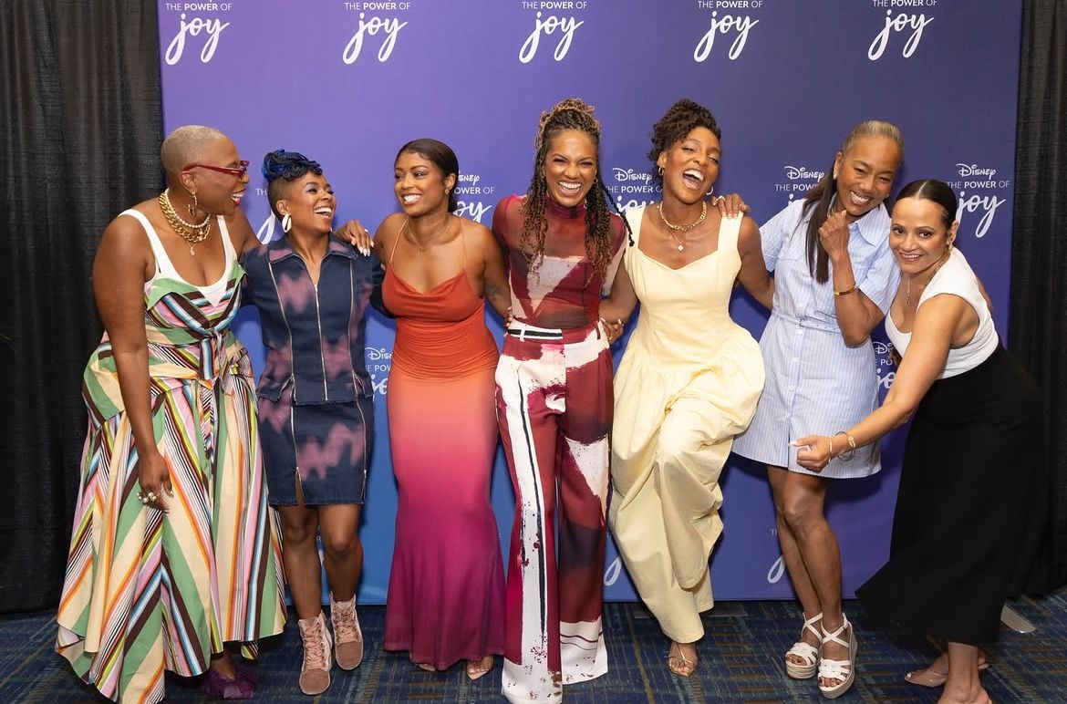 Group photo against purple step-and-repeat banner at entertainment industry event.