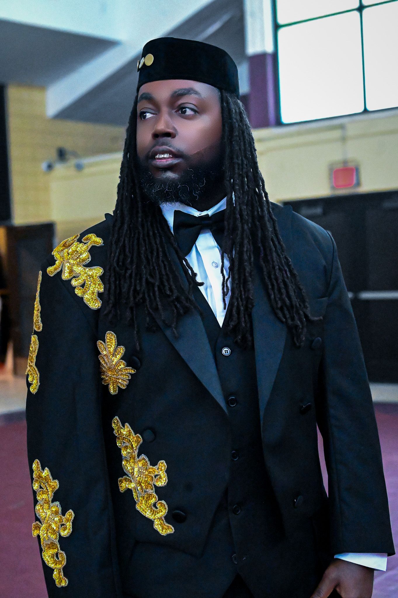 Formal black suit with gold embroidered accents and white dress shirt.