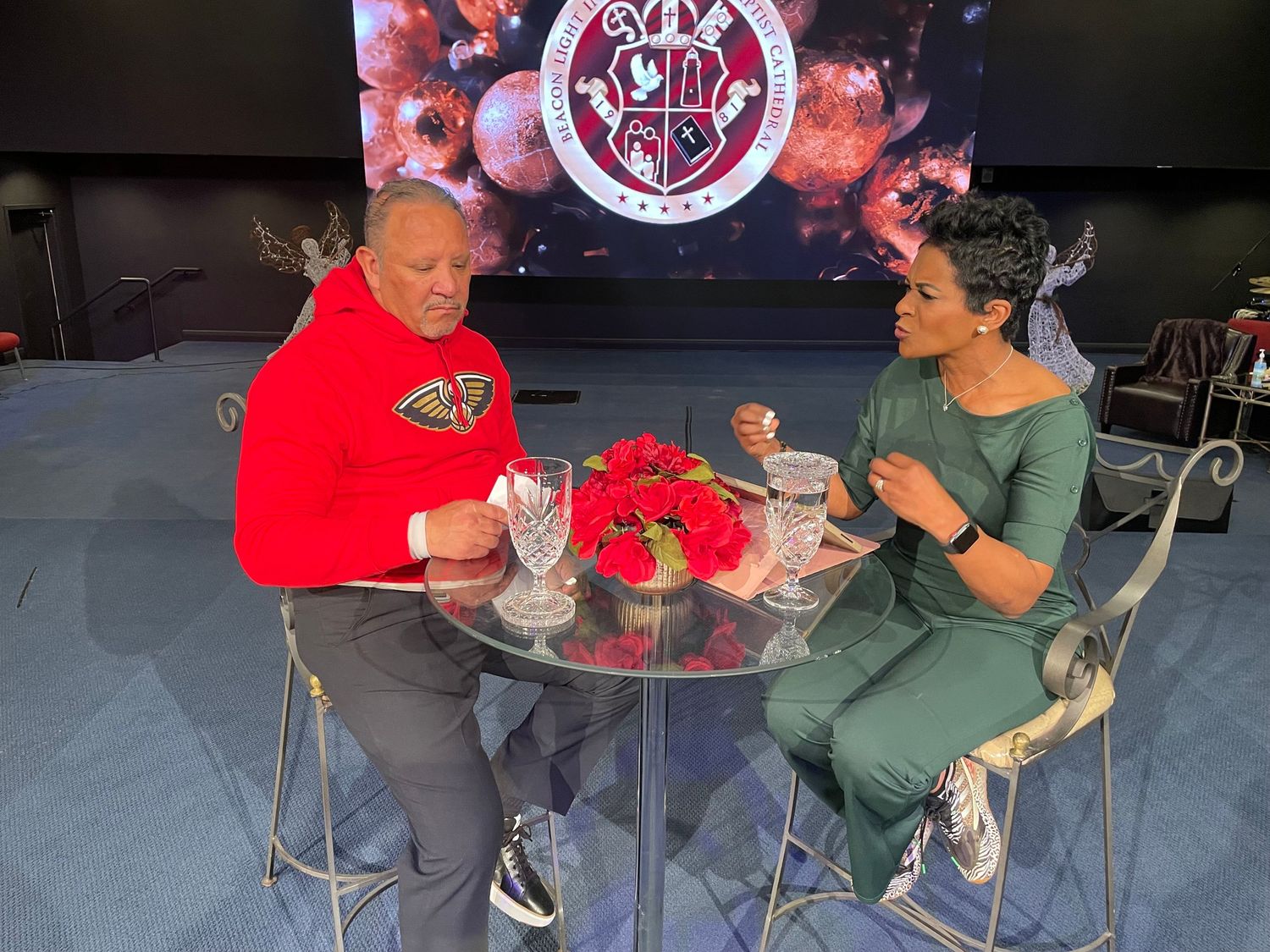 Two people enjoying food at a table with red digital display in background.