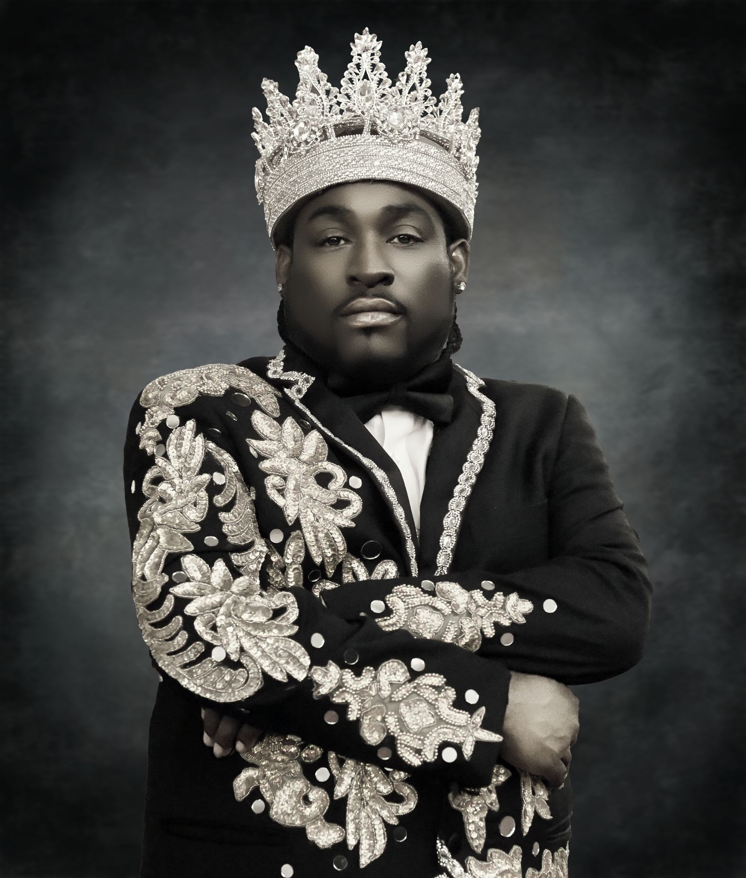 A dramatic black and white portrait with ornate crown and embellished details.
