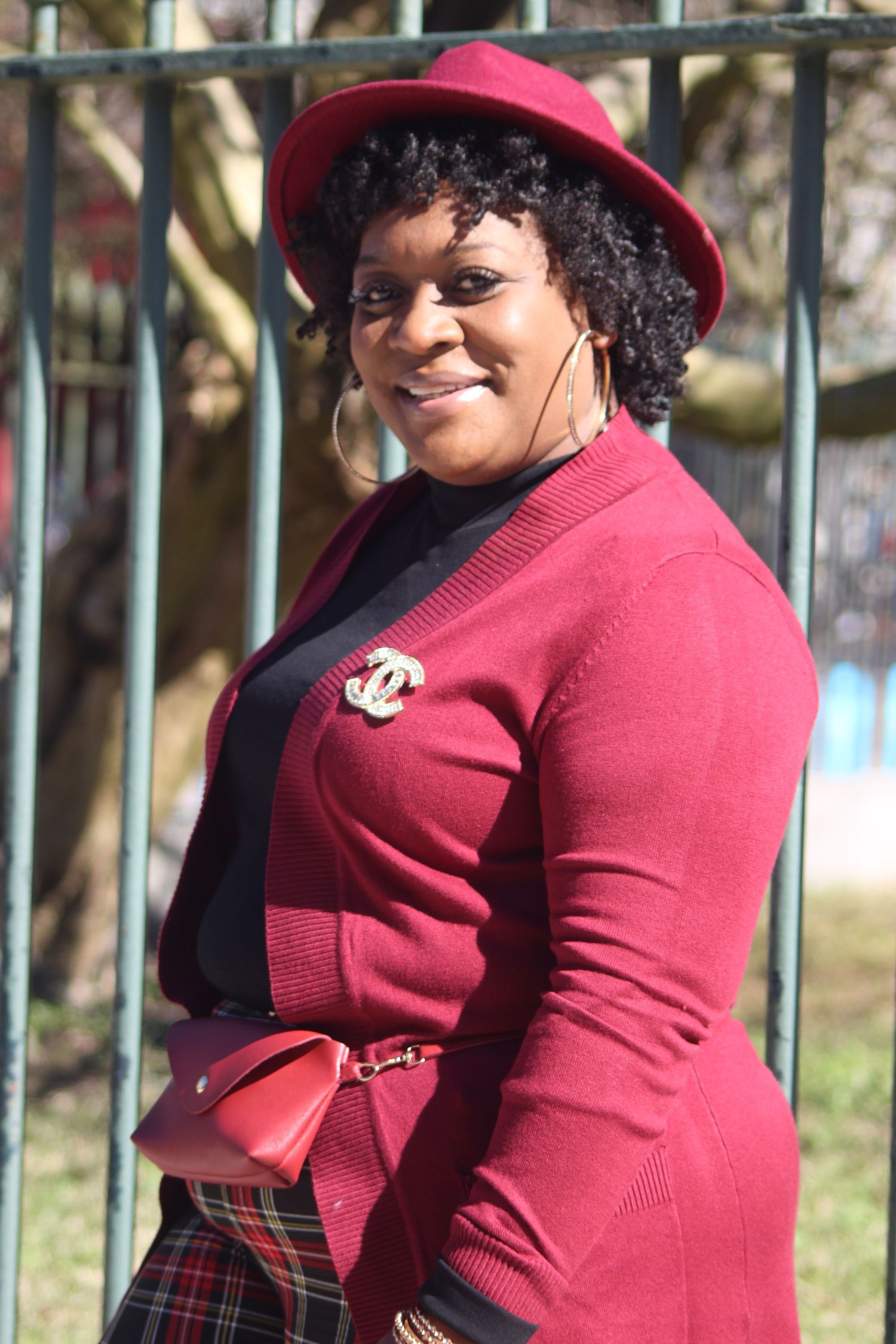 A stylish outfit featuring a red hat and matching sweater with decorative brooch.