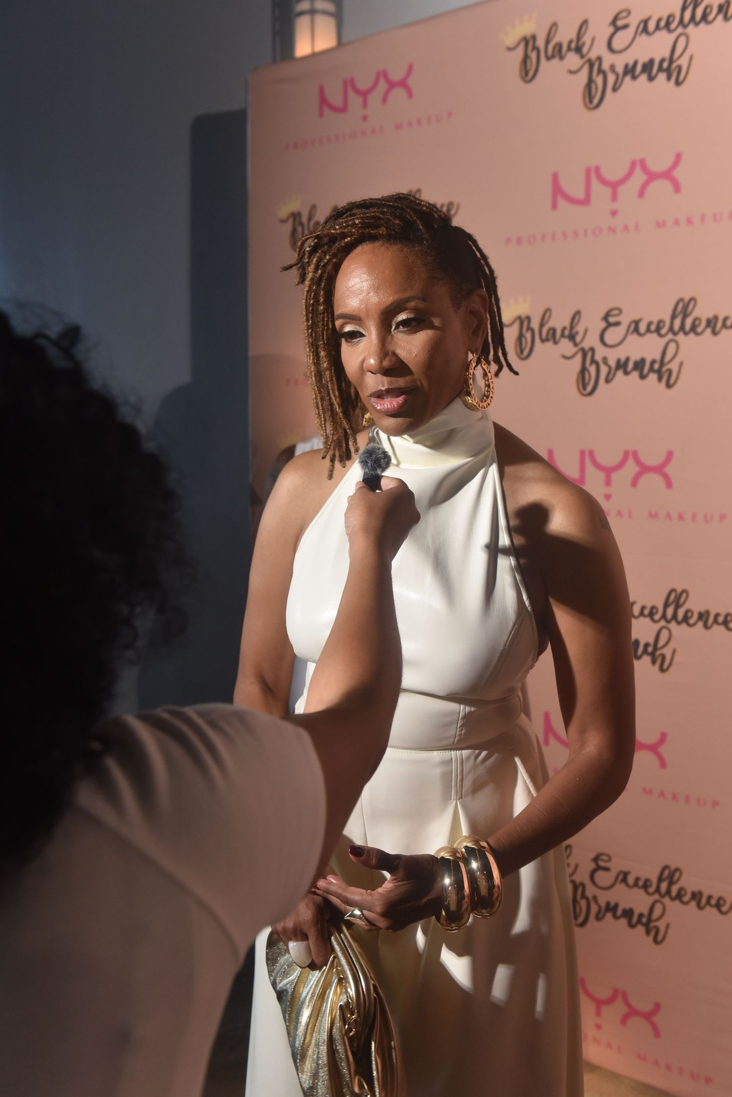 Woman in white dress being interviewed at NYX Professional Makeup Black Excellence Brunch event.