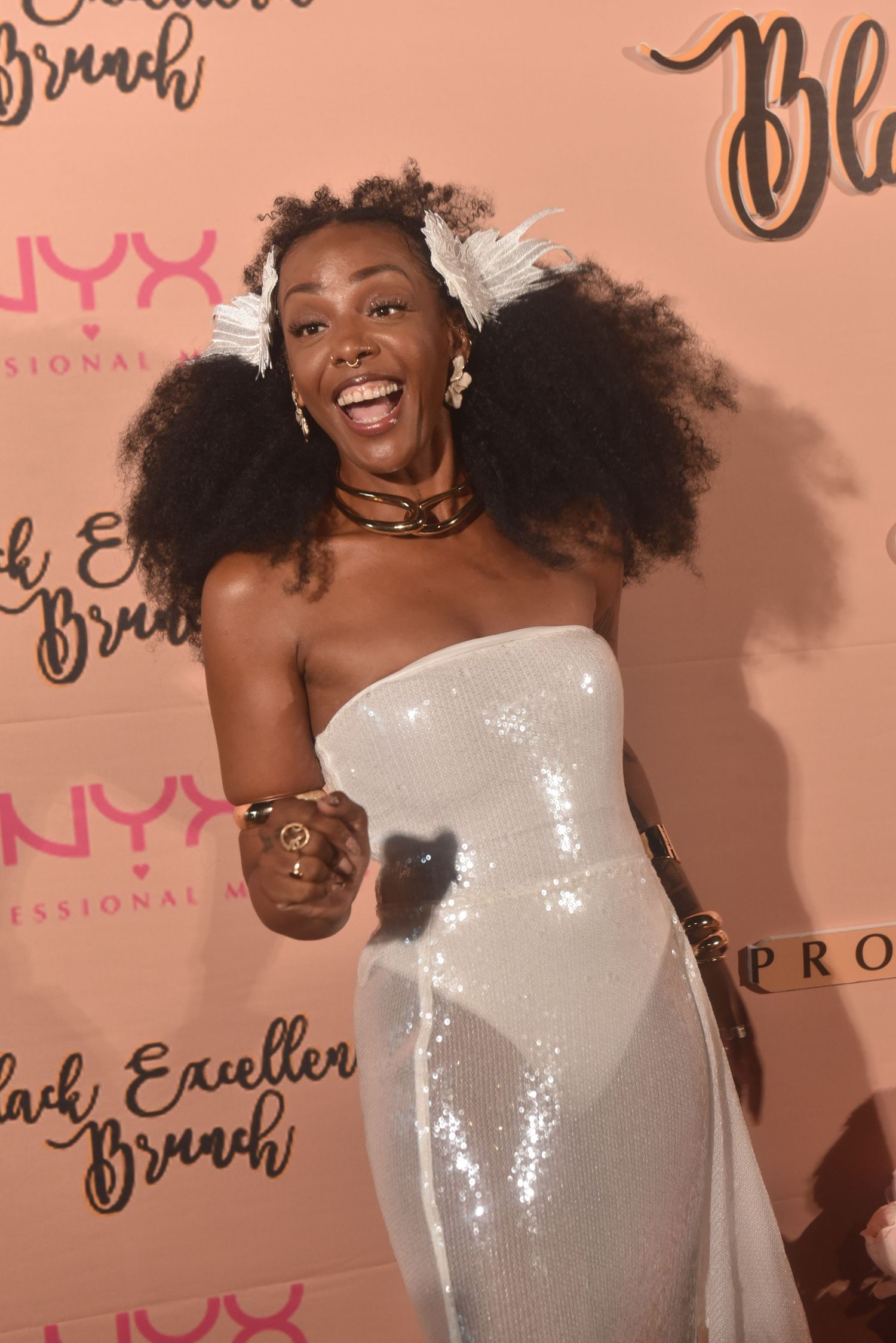 Woman in white sequin strapless gown laughing at NYX Professional Makeup Black Excellence Brunch event.