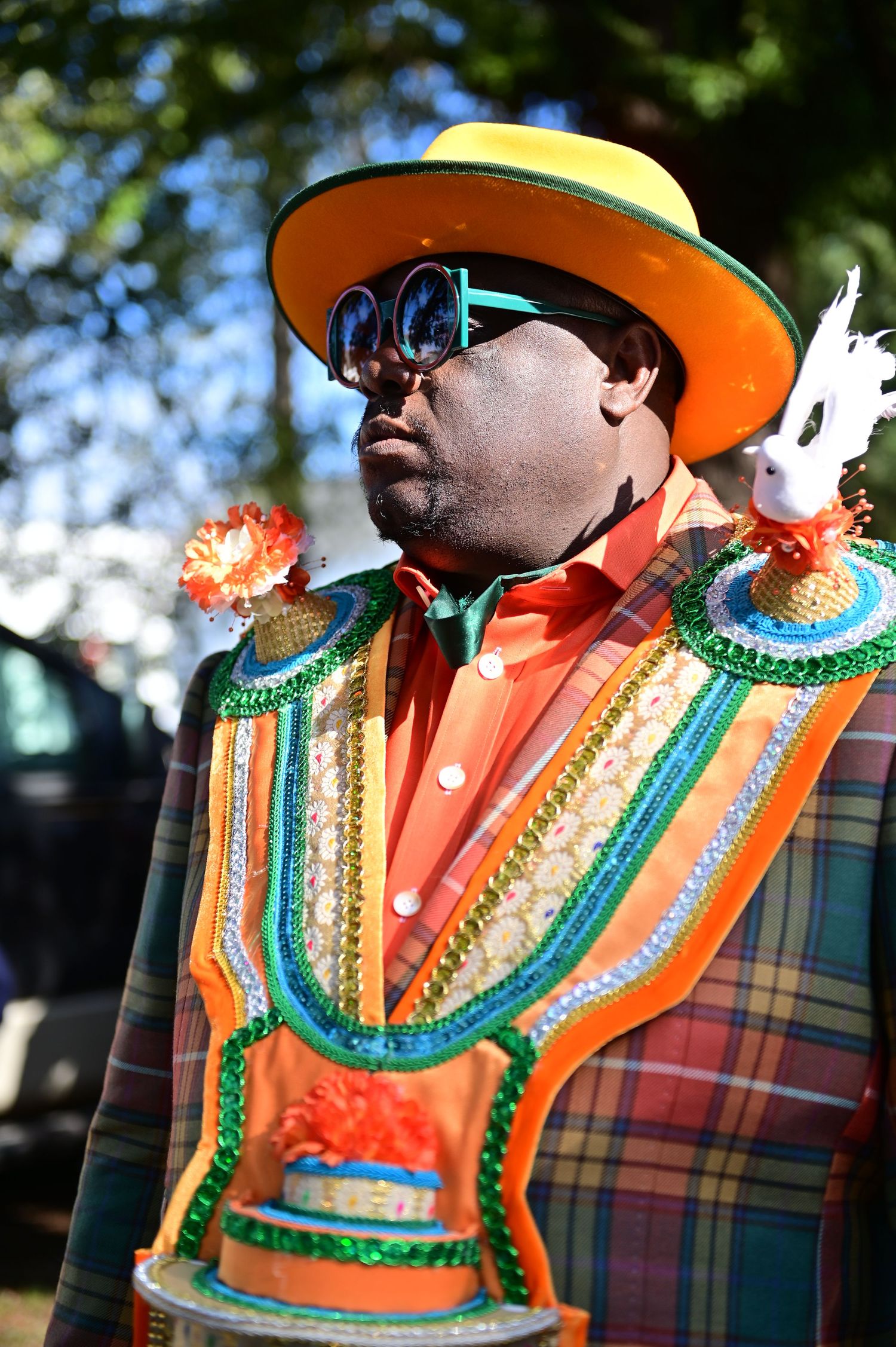 Close-up of performer in plaid jacket with decorative vest and orange hat.