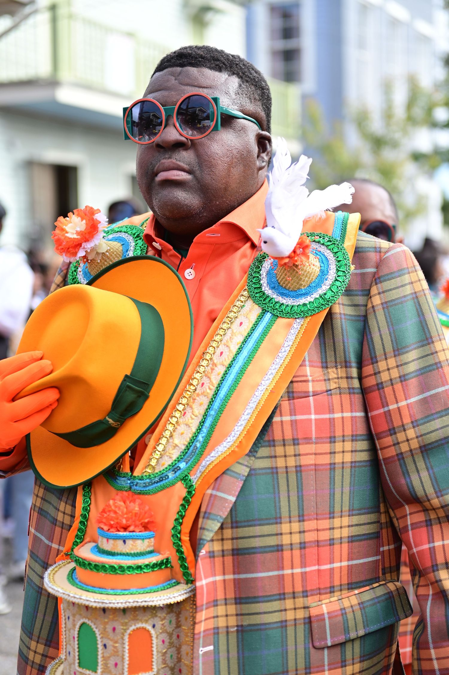 Parade participants wearing orange outfits with elaborate green and gold trimmed collars.