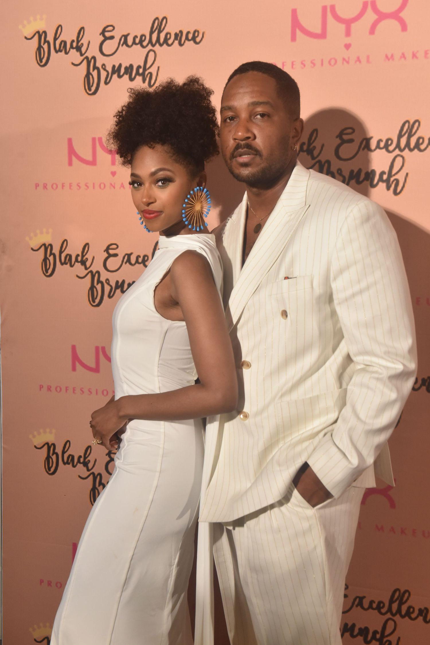 Elegant couple in white outfits posing at Black Excellence Brunch event sponsored by NYX Professional Makeup.