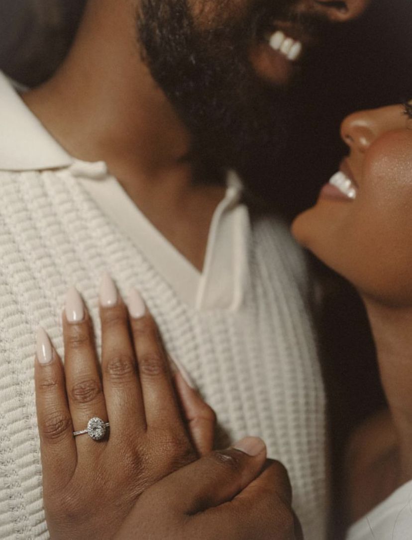 Close-up shot of hands displaying engagement ring with warm intimate styling.