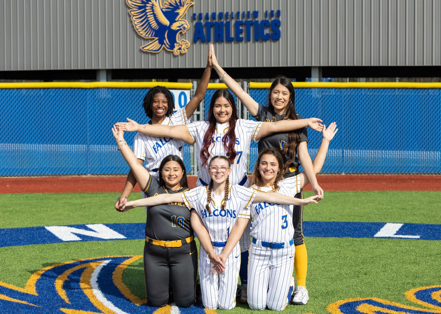 Team photo session on baseball field with blue turf and yellow accents.
