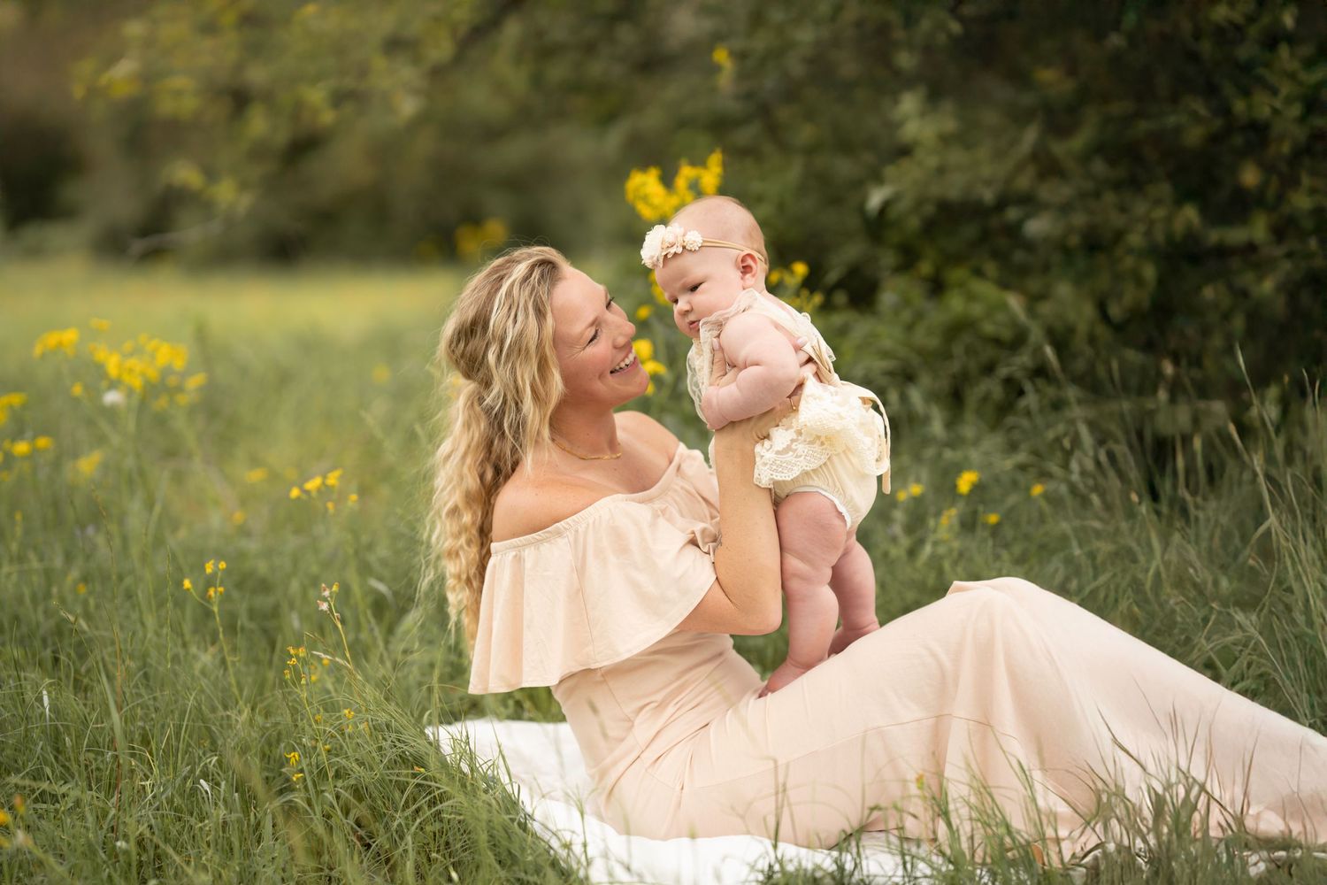 A joyful moment shared between two people sitting on a blanket in a grassy meadow with yellow wildflowers in the background.