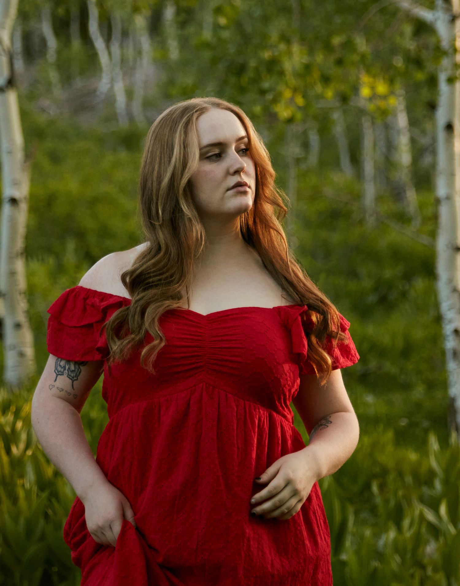 A close-up outdoor portrait featuring a red dress against a backdrop of aspen trees.