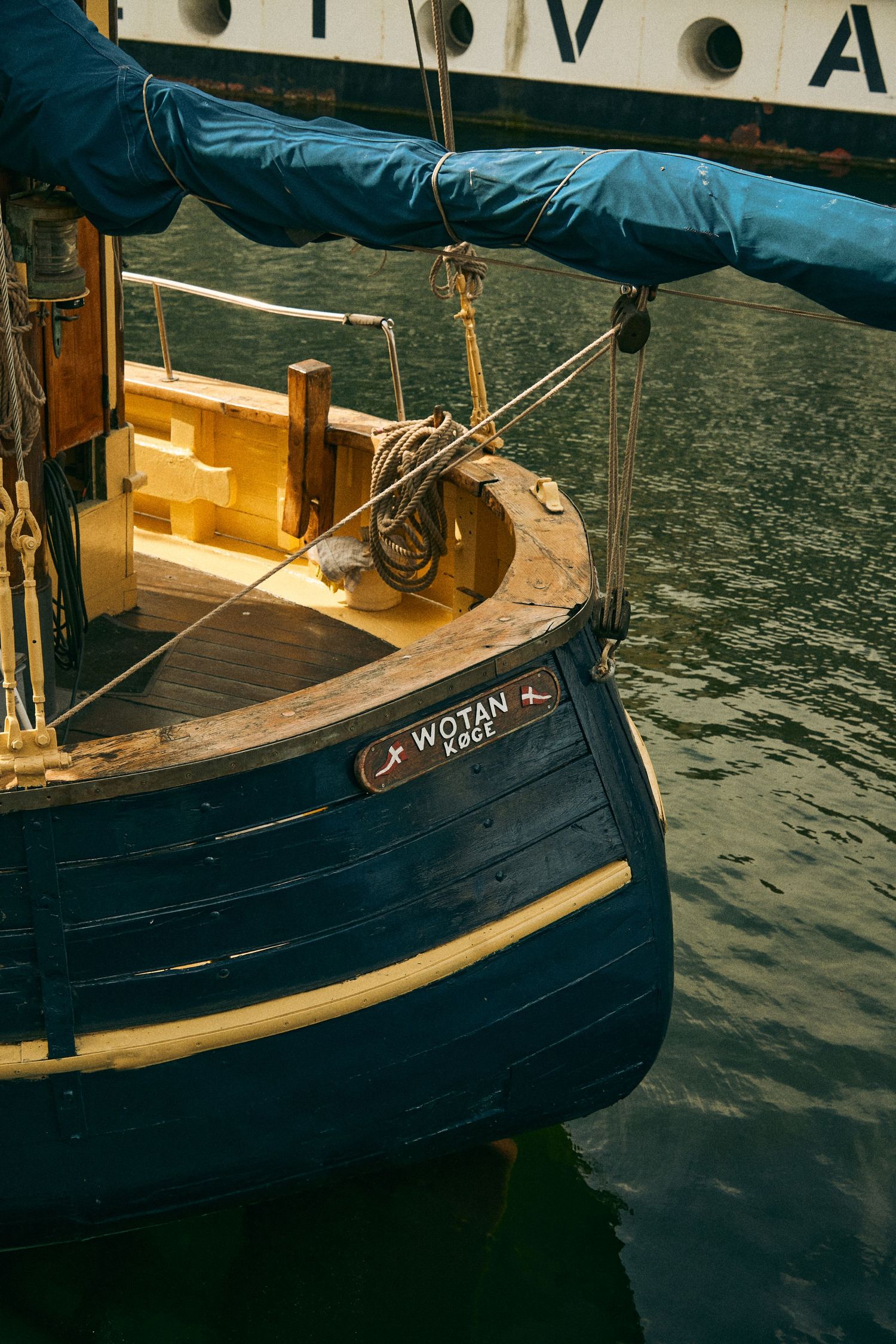 Close-up of a vintage blue wooden boat's stern with nautical details and ropes.