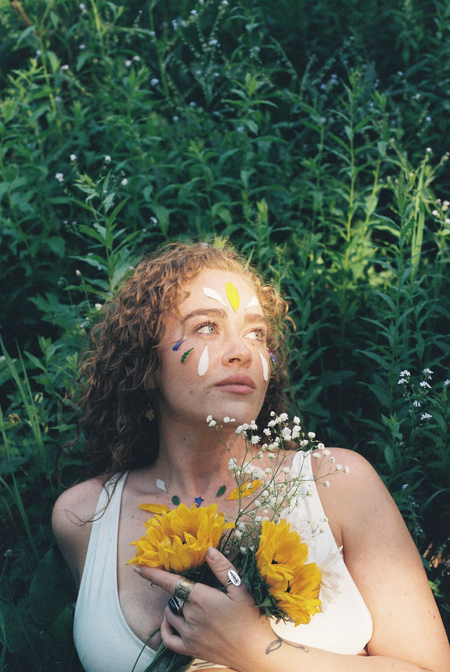 Ethereal summer portrait with sunflowers and baby's breath flowers against lush green foliage.
