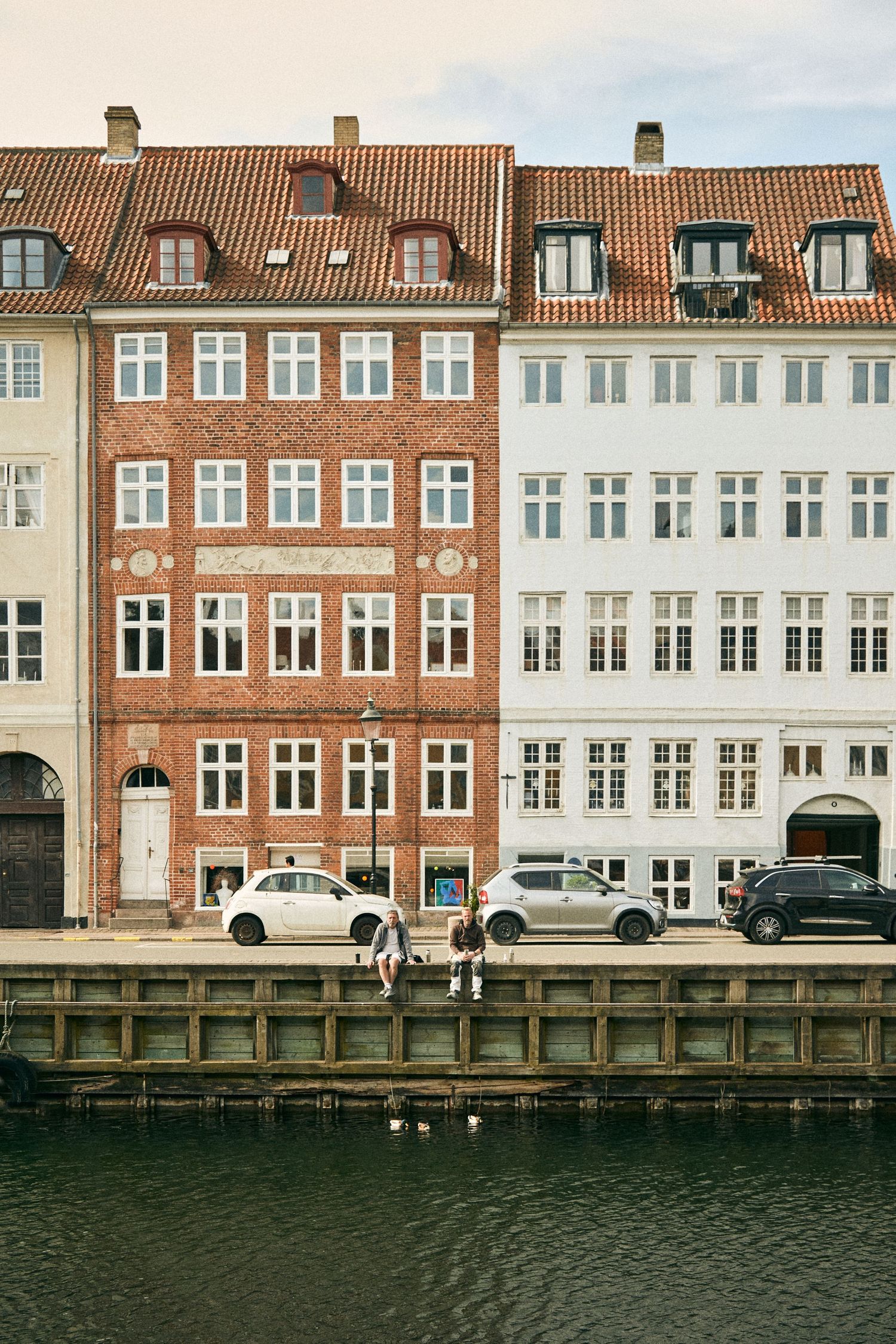 Historic Danish buildings with traditional architecture line a waterfront canal in Copenhagen.