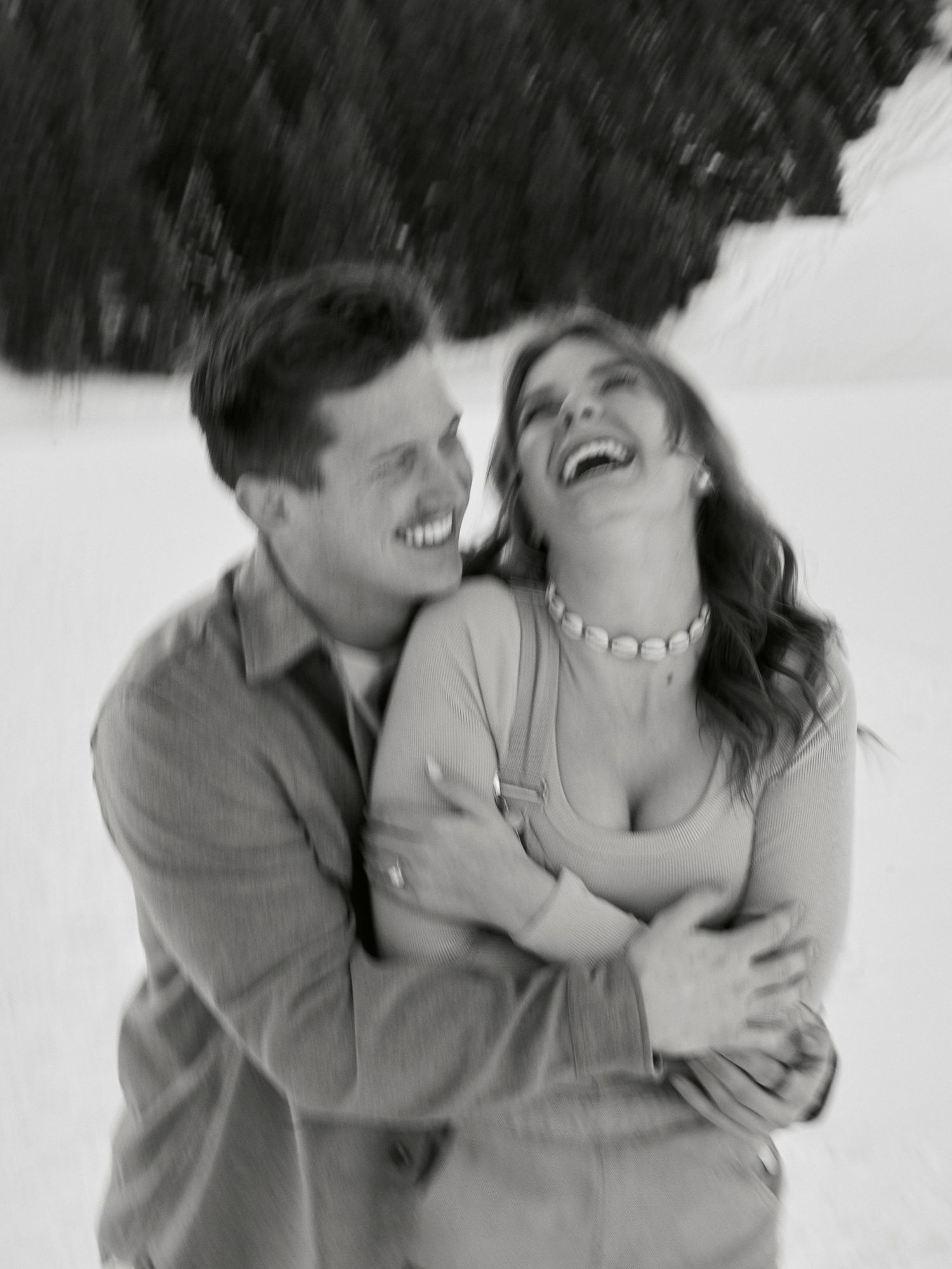 A joyful intimate moment captured in black and white as a couple shares laughter together.