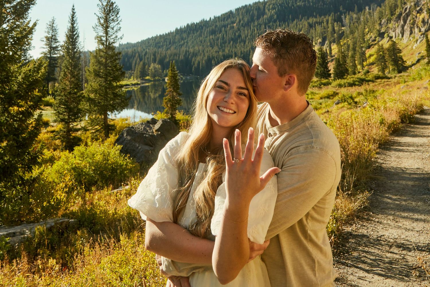 Joyful moment shared on a mountain trail with scenic lake views.