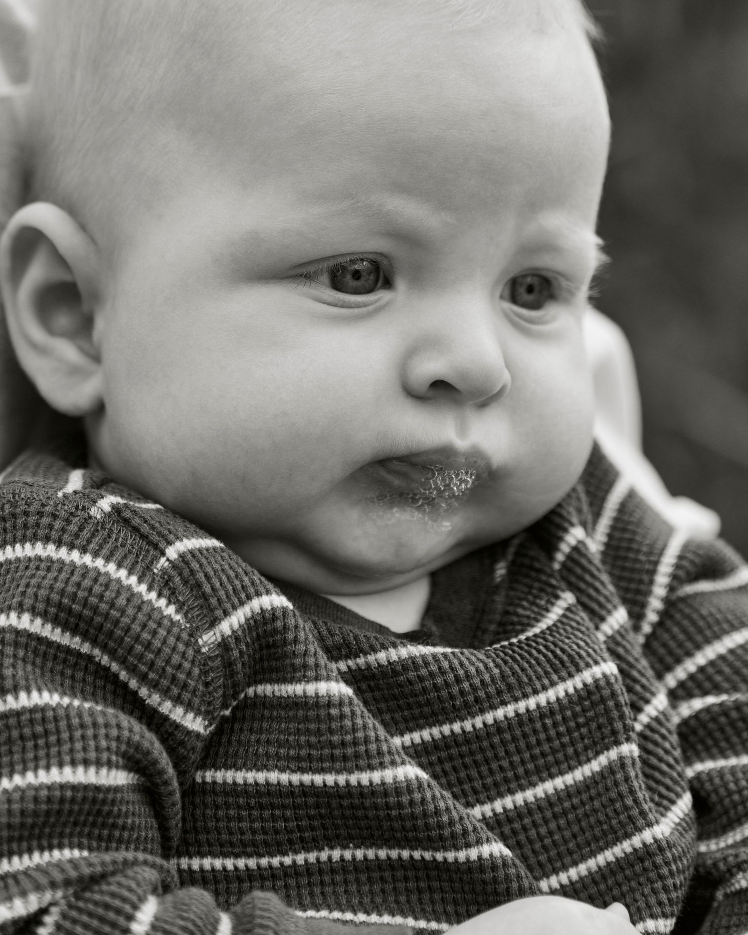 Black and white portrait of a baby in a striped sweater with chubby cheeks.