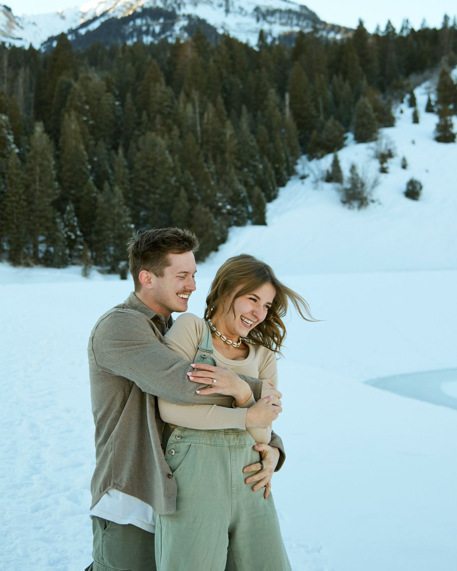 Joyful winter moment captured against snow-covered mountains and evergreen forest.