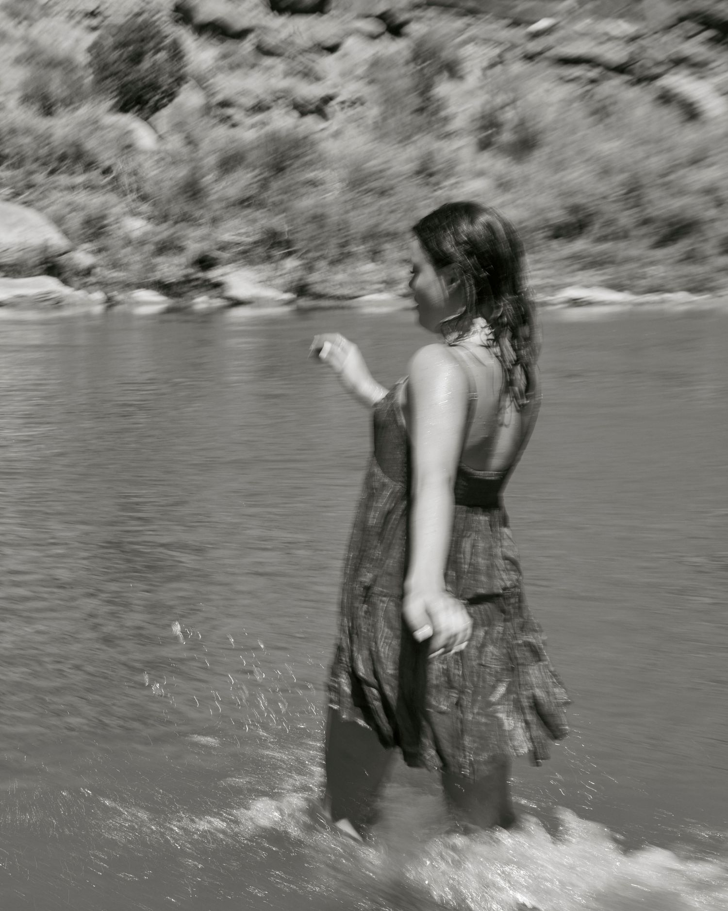 Black and white photograph of someone splashing in river water near canyon walls.