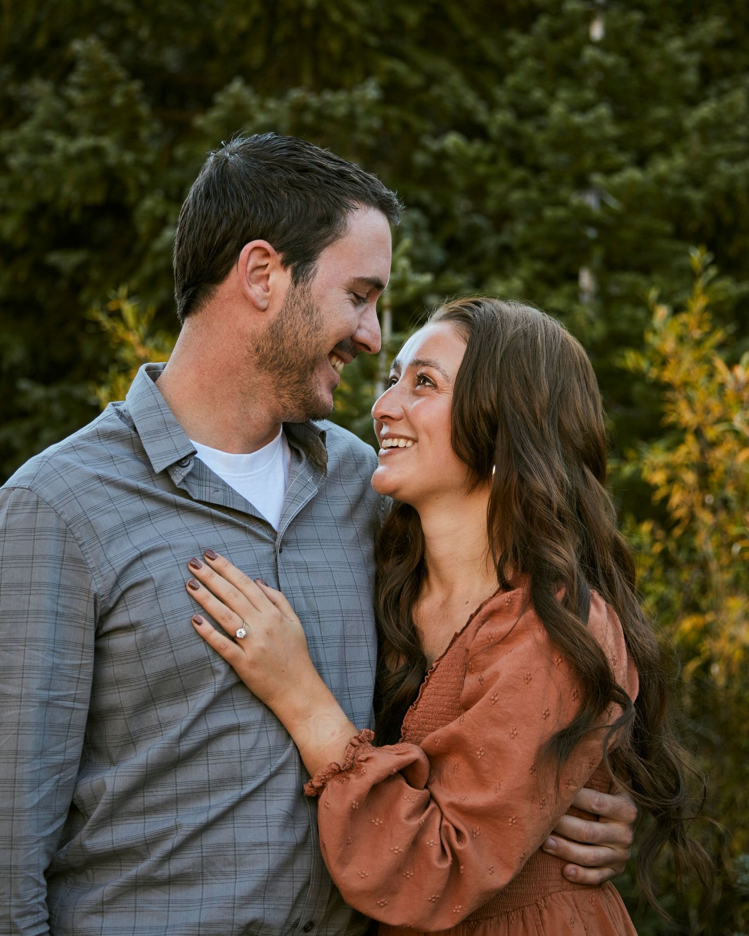 A couple laughs together while embracing outdoors in autumn.