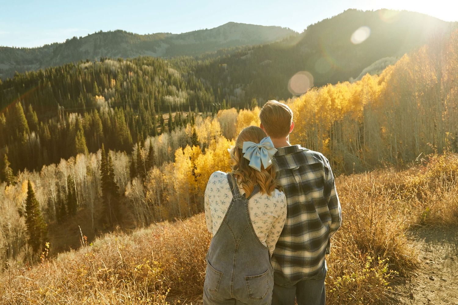 Couple sharing intimate moment against mountainous landscape during golden sunset.
