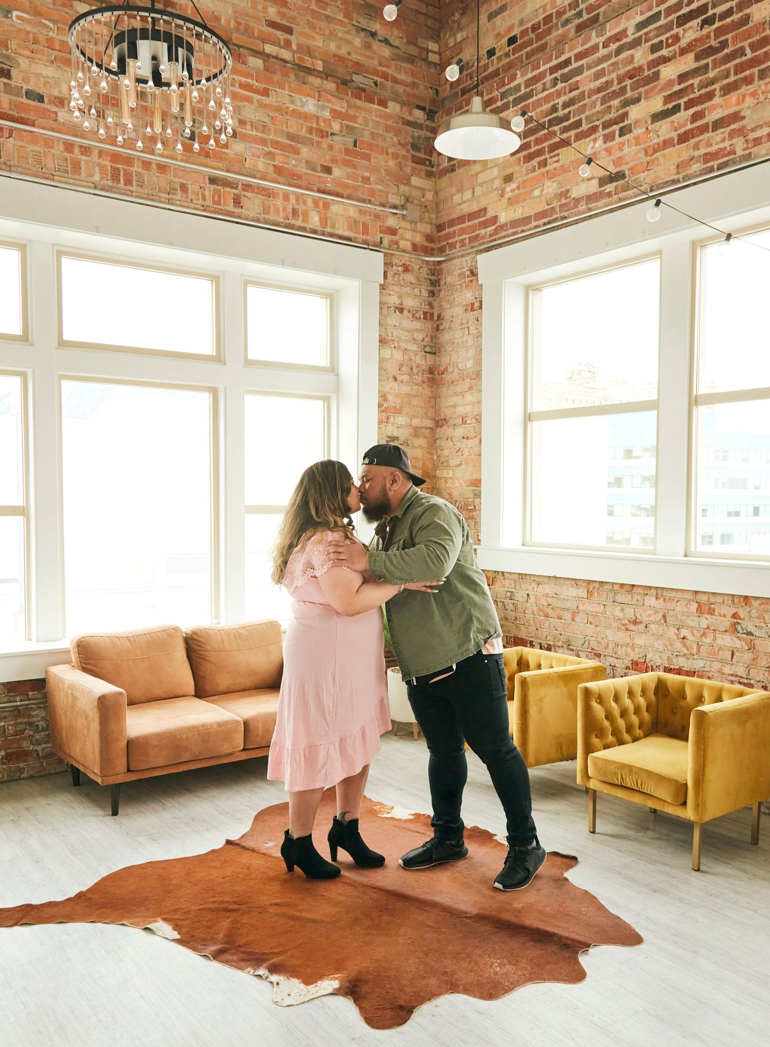 An intimate dance moment in a sunlit room with exposed brick walls and vintage furnishings.