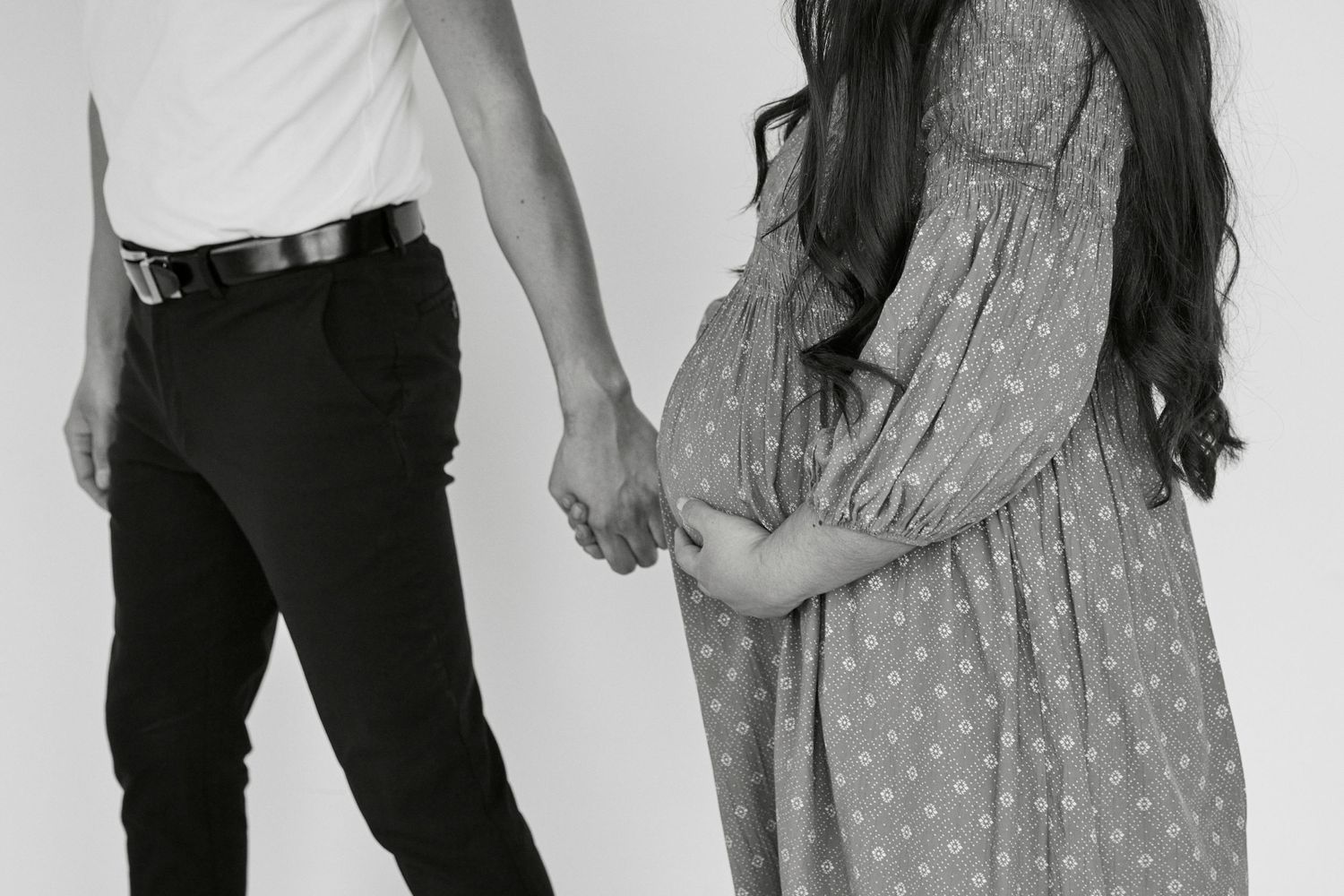 Black and white portrait of a couple in polka dot dress and white polo holding hands.