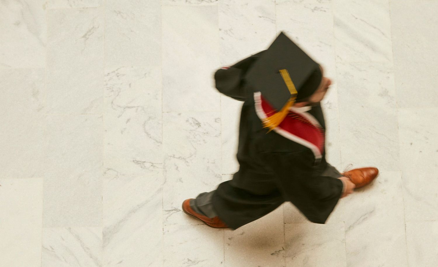 Graduation cap and gown arranged artistically on white background.