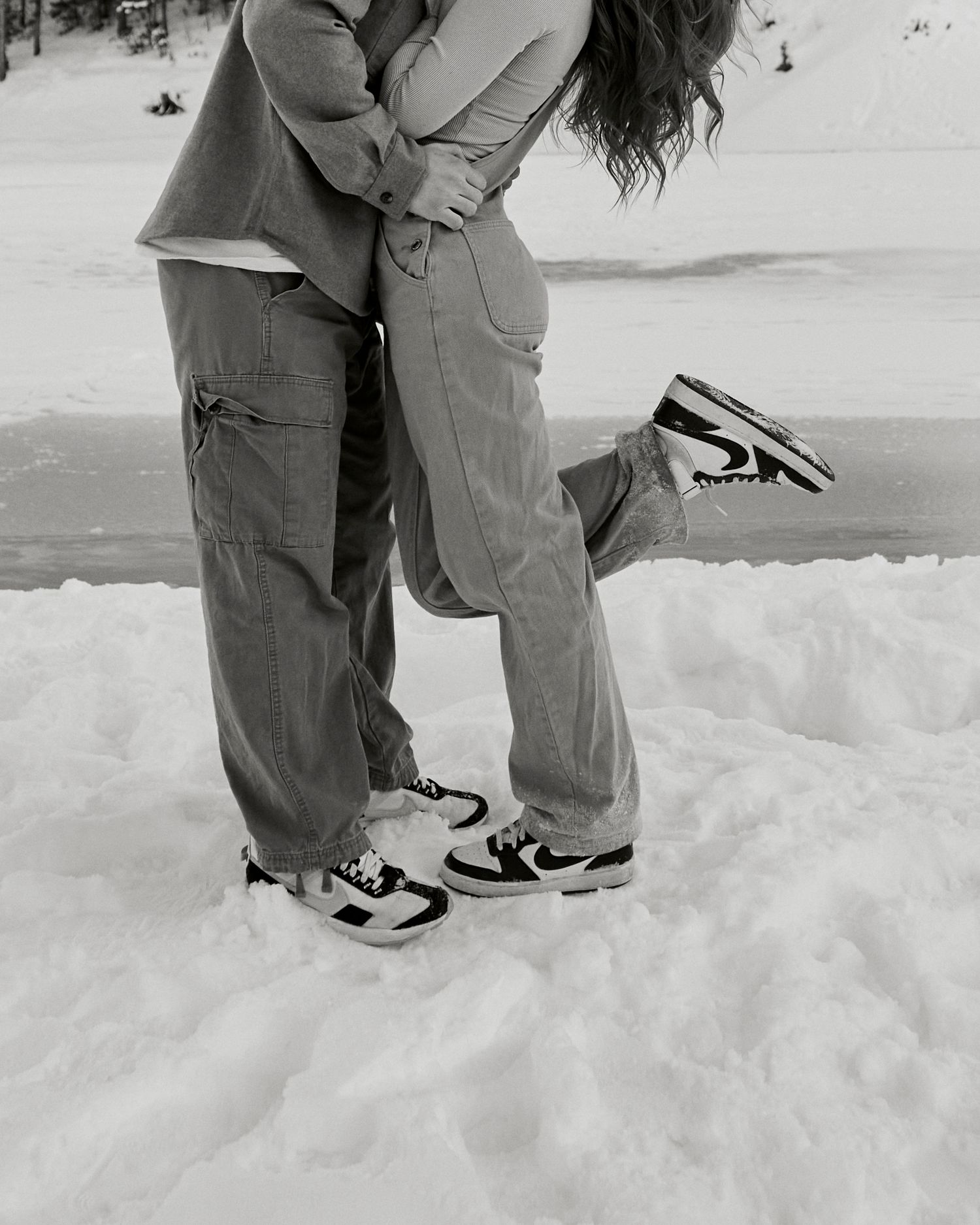 Close-up of two pairs of Nike sneakers in the snow during an intimate moment.