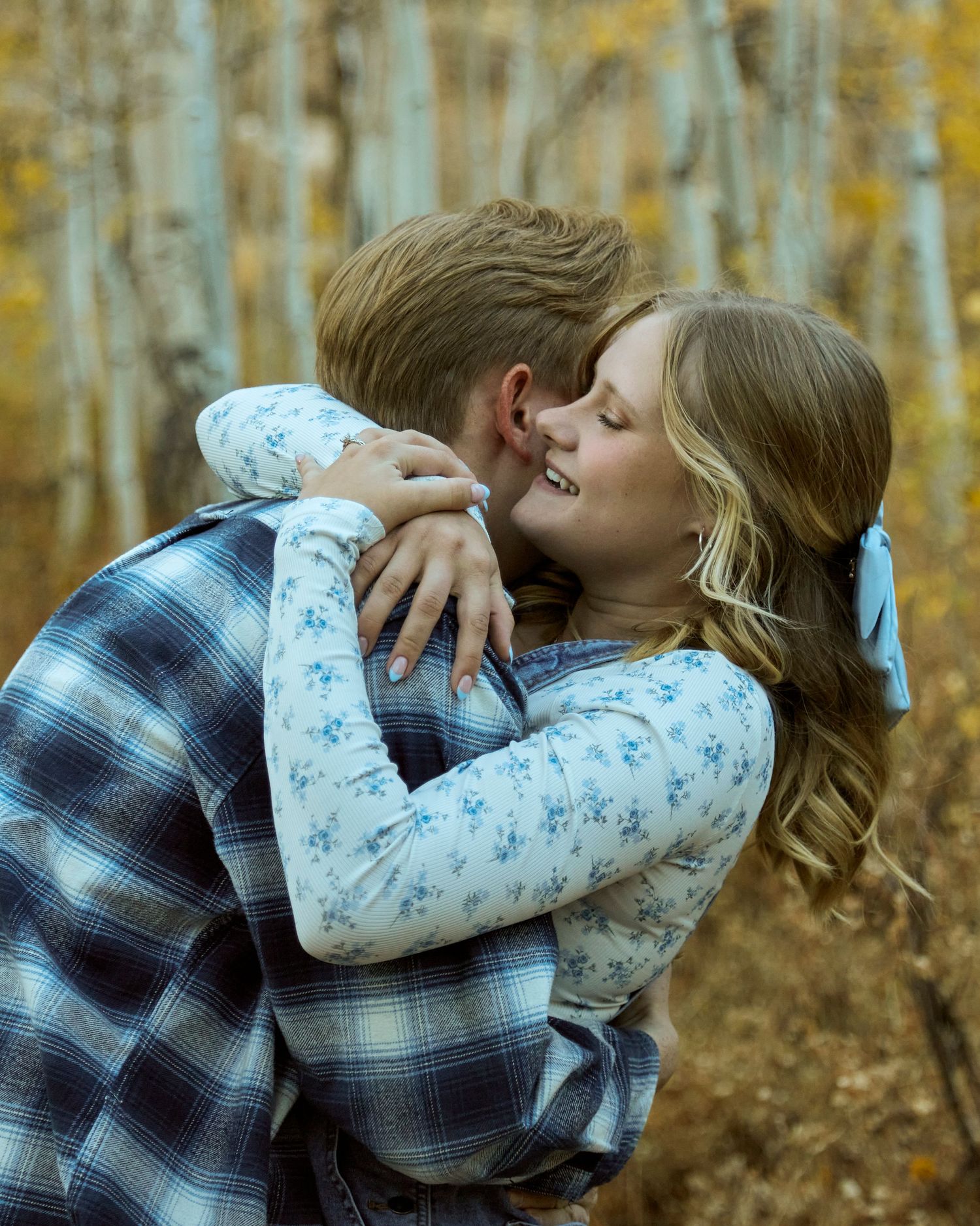 Romantic couple embracing in an autumn forest with golden aspen trees in the background.