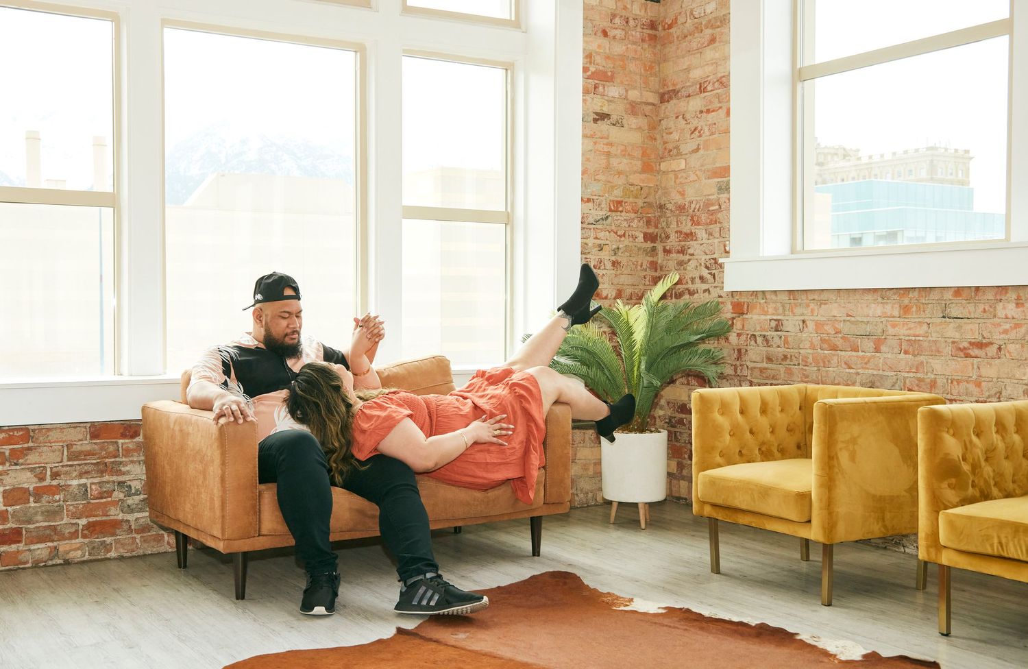 A relaxed scene in a bright room with exposed brick walls and modern furniture.