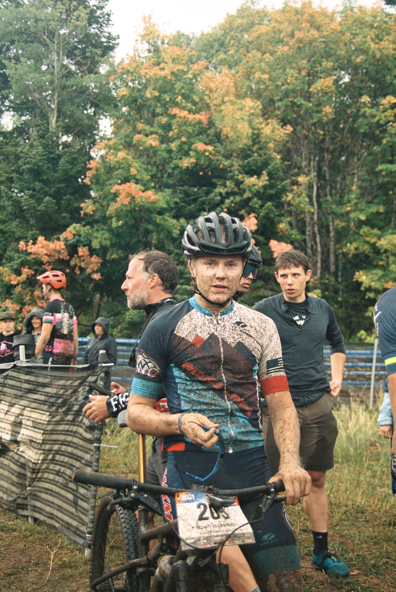 Mountain bike racer at outdoor competition event surrounded by autumn foliage.