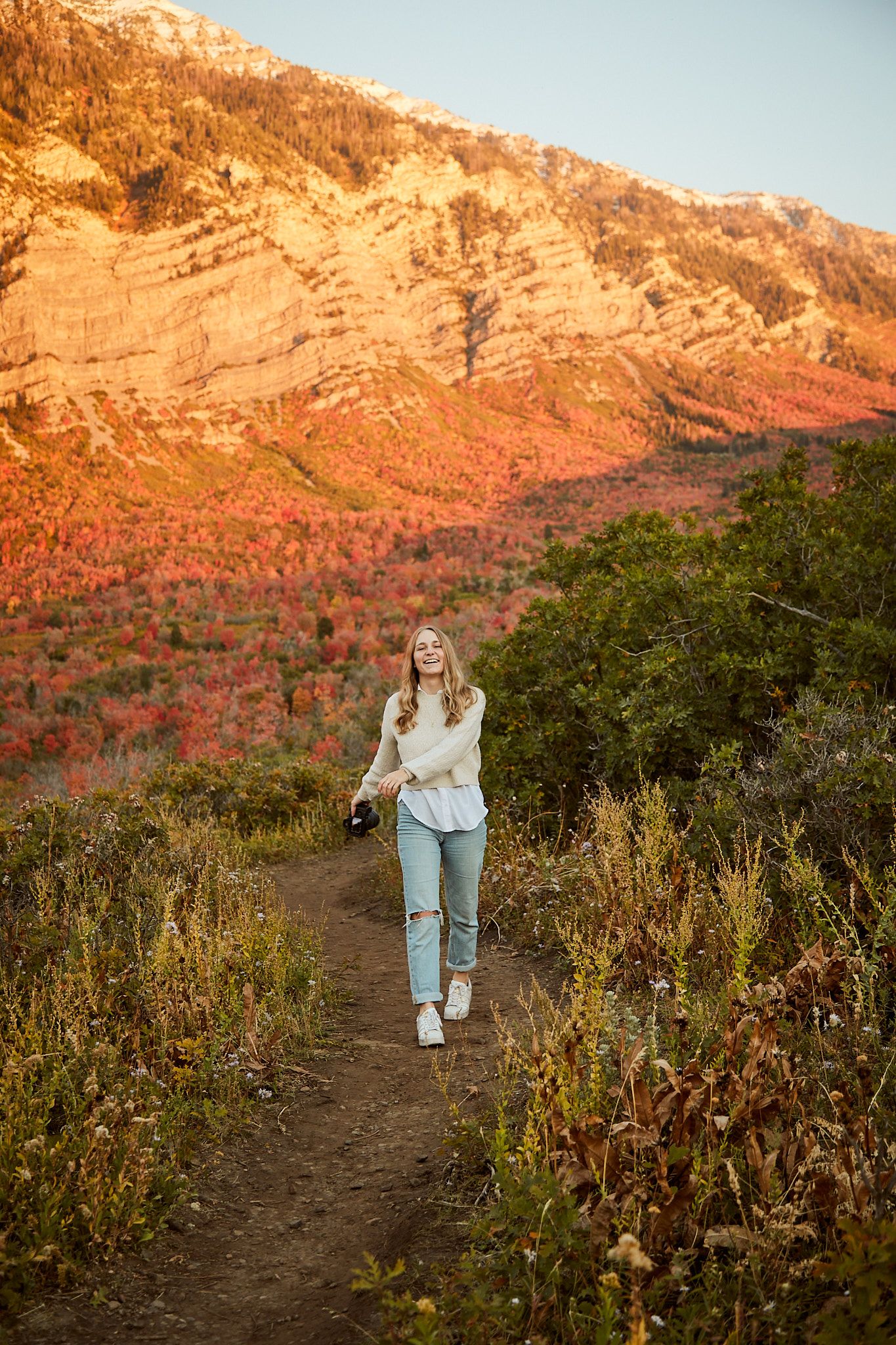 Hiking portrait on mountain trail during golden hour with dramatic red rock formations.