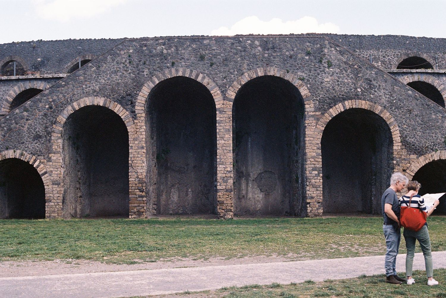 Ancient stone archways of a Roman amphitheater with visitors viewing the historic structure.