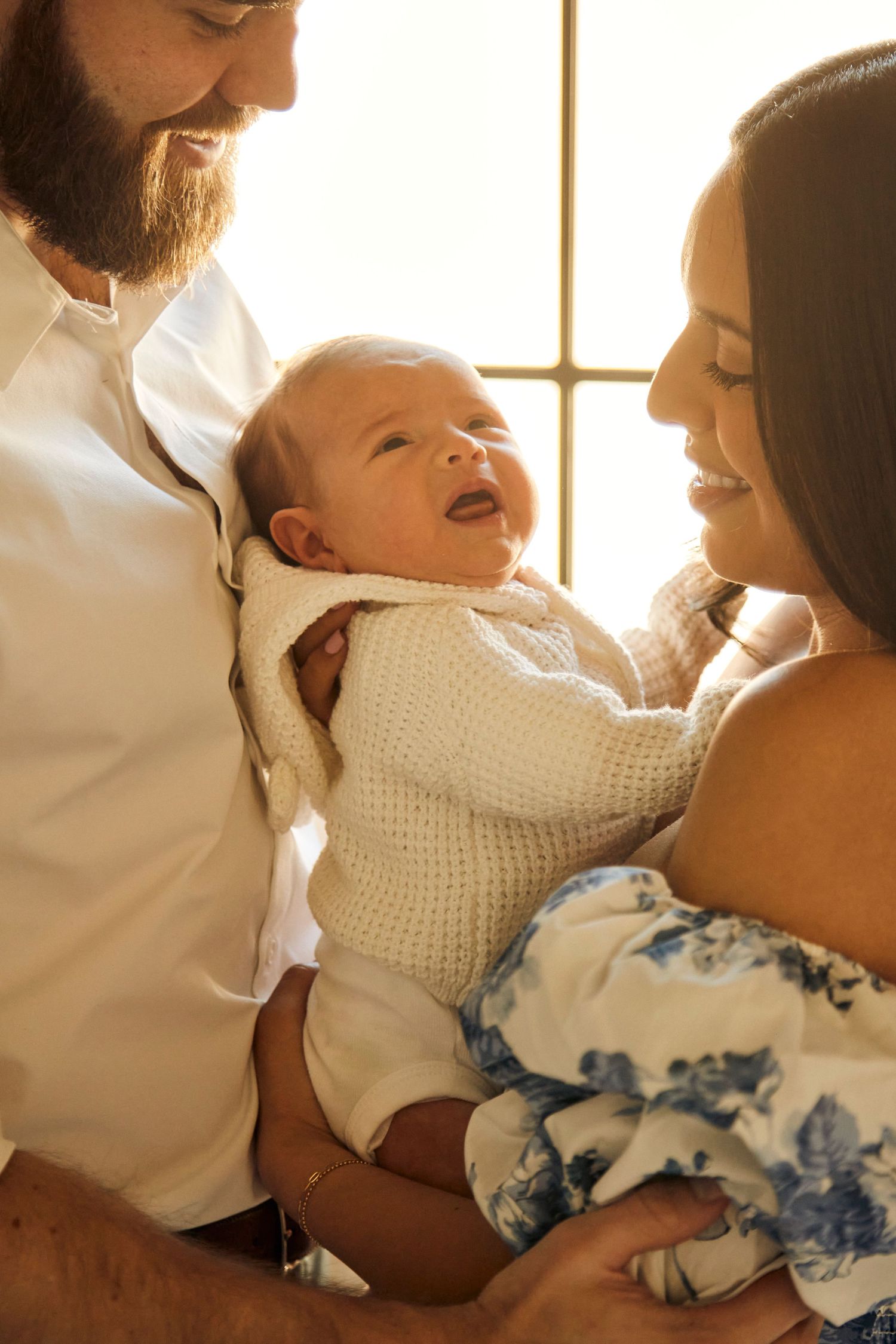 Happy family shares joyful moment with laughing baby in sunlit room.