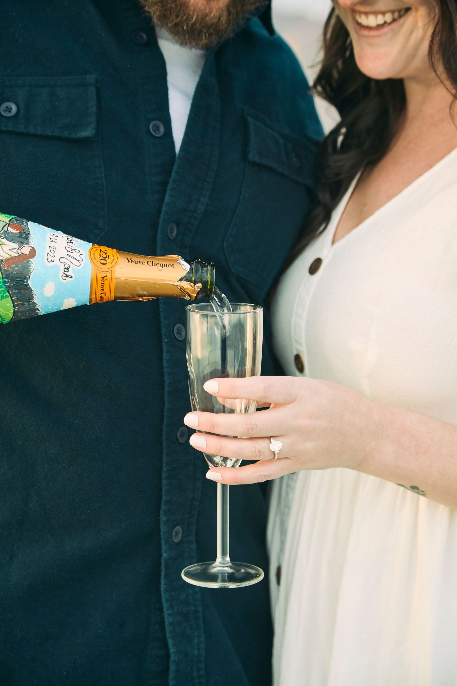 Intimate moment of pouring champagne into a glass during engagement celebration.