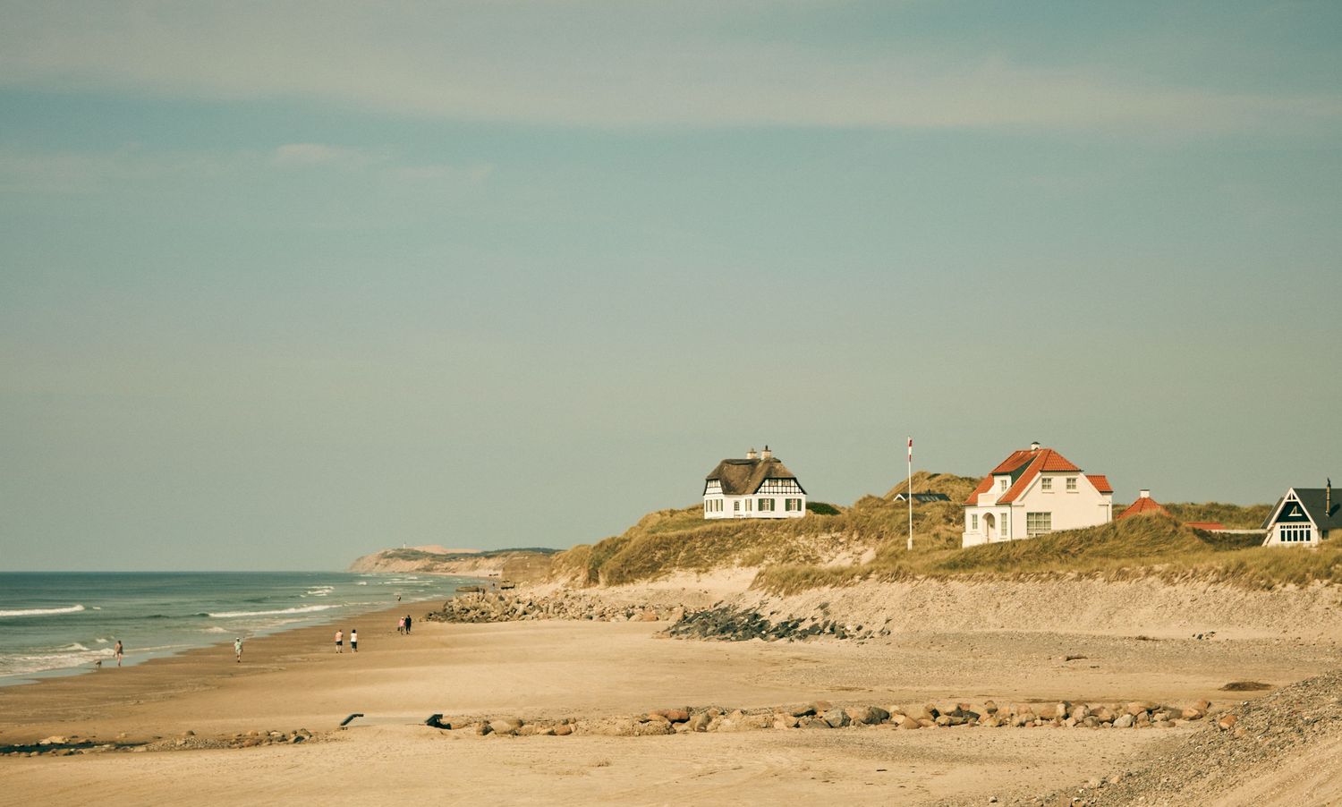Coastal beach houses perched on sand dunes overlooking the ocean.