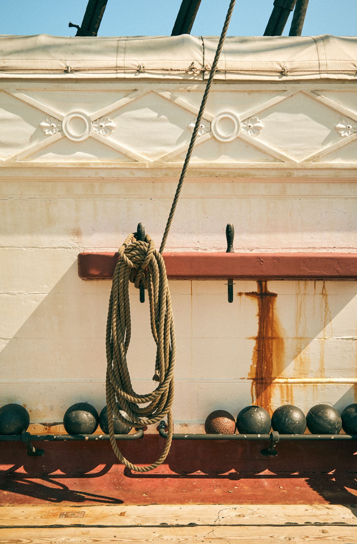 Nautical rope and black round fenders hanging on the white side of a ship.