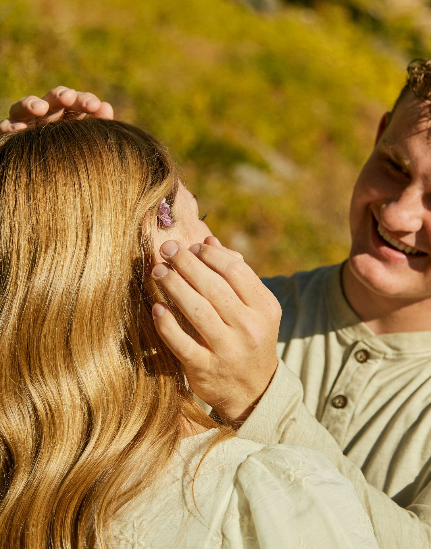 Tender moment captured in warm sunlight against a natural backdrop.