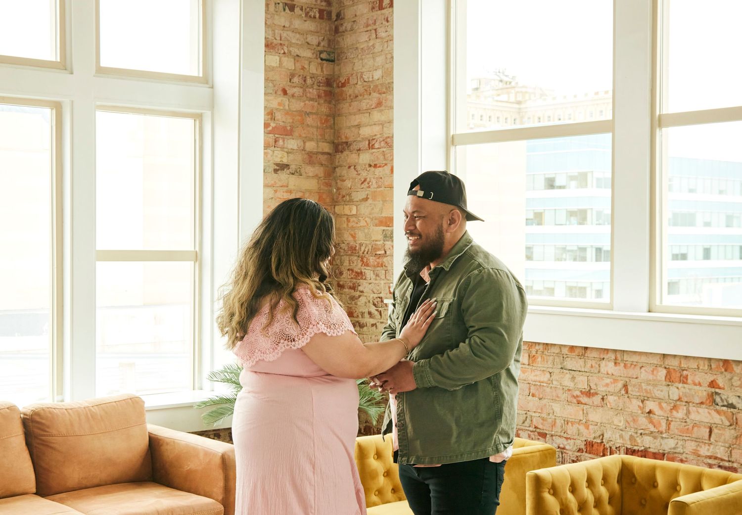 A sweet moment shared between two people in a bright industrial-style room with brick walls.