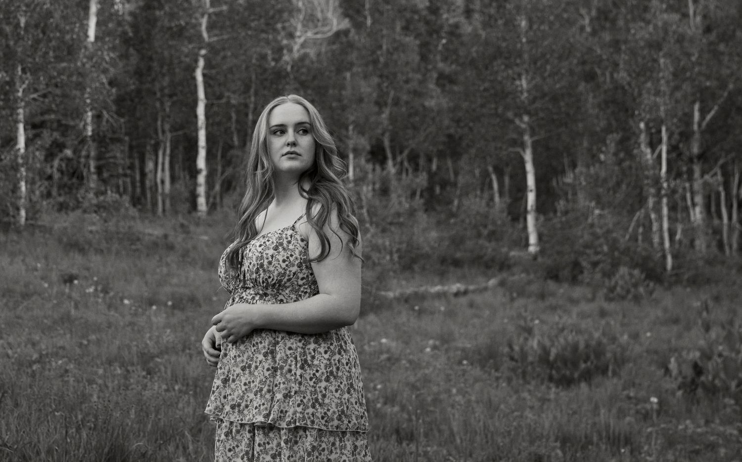 A black and white portrait in a mountain setting with aspen trees in the background.