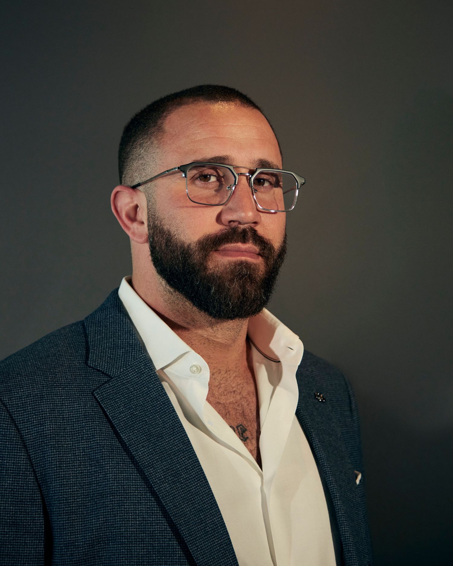 Professional portrait of a man in a blazer and glasses with a well-groomed beard.