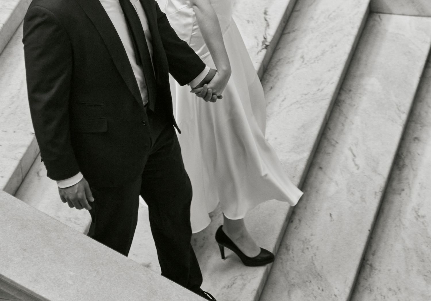 A black and white photo showing formal shoes and dress attire on stone steps.
