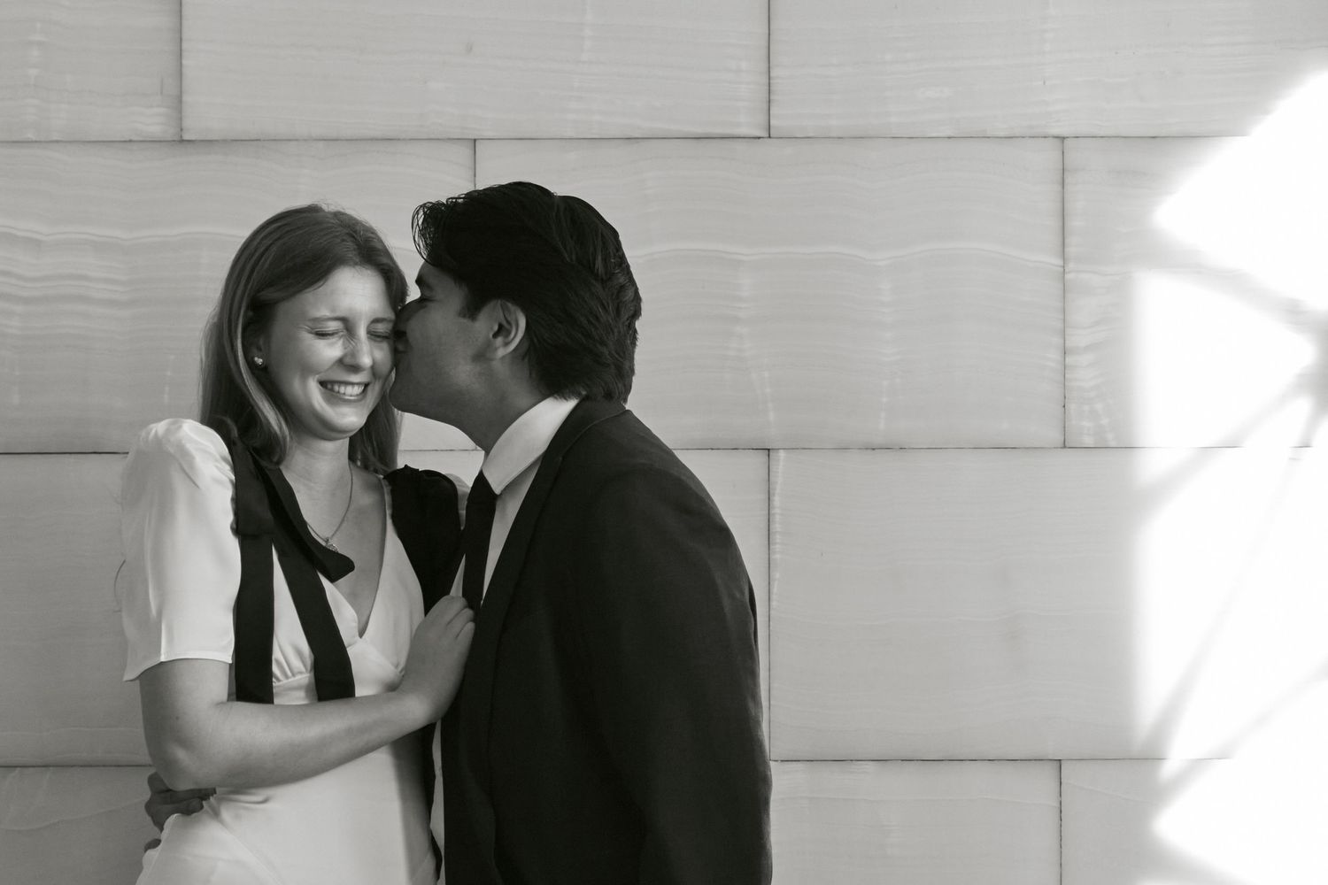 A tender black and white moment captured against a stone wall background.