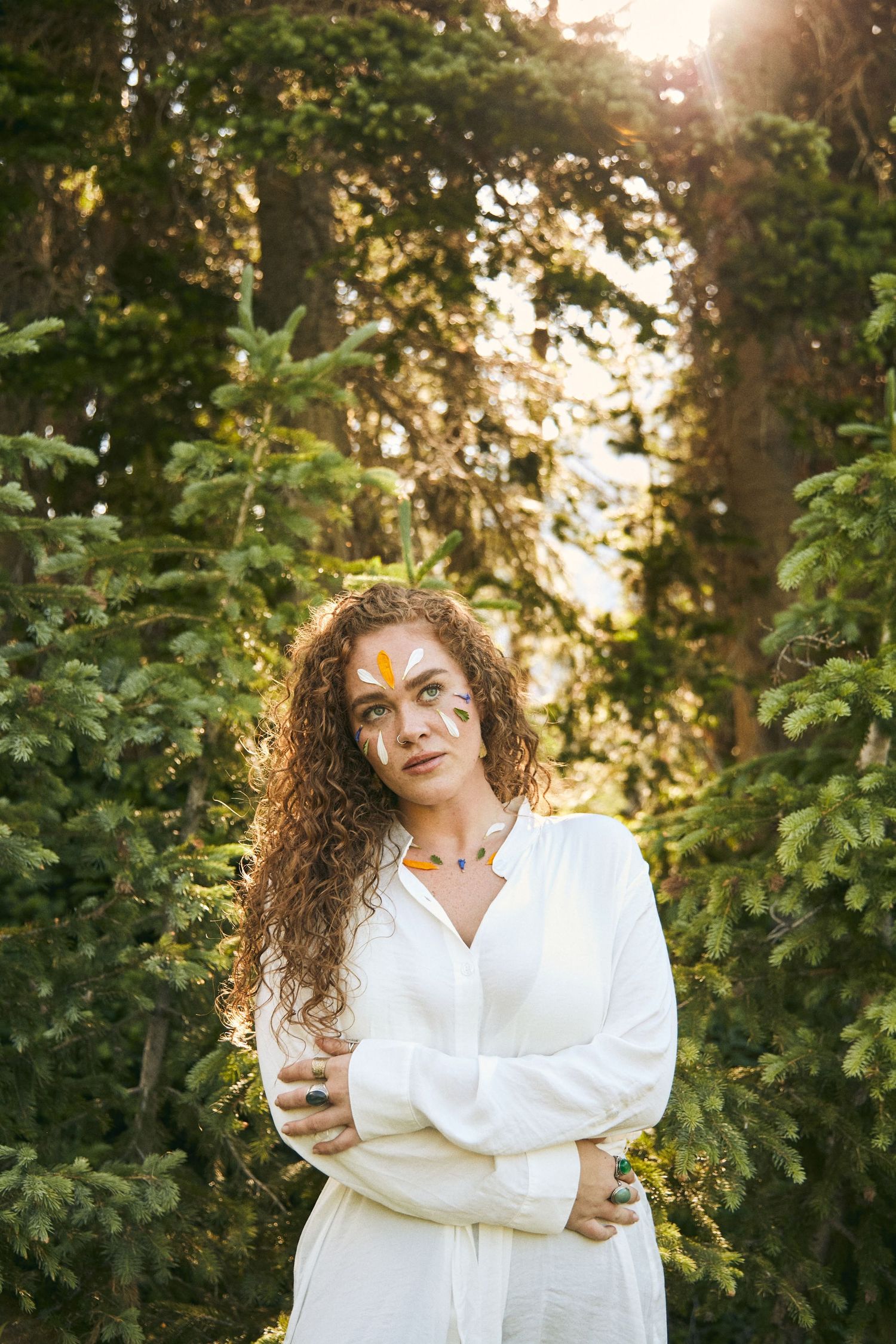 Portrait in white clothing against lush green foliage at golden hour.