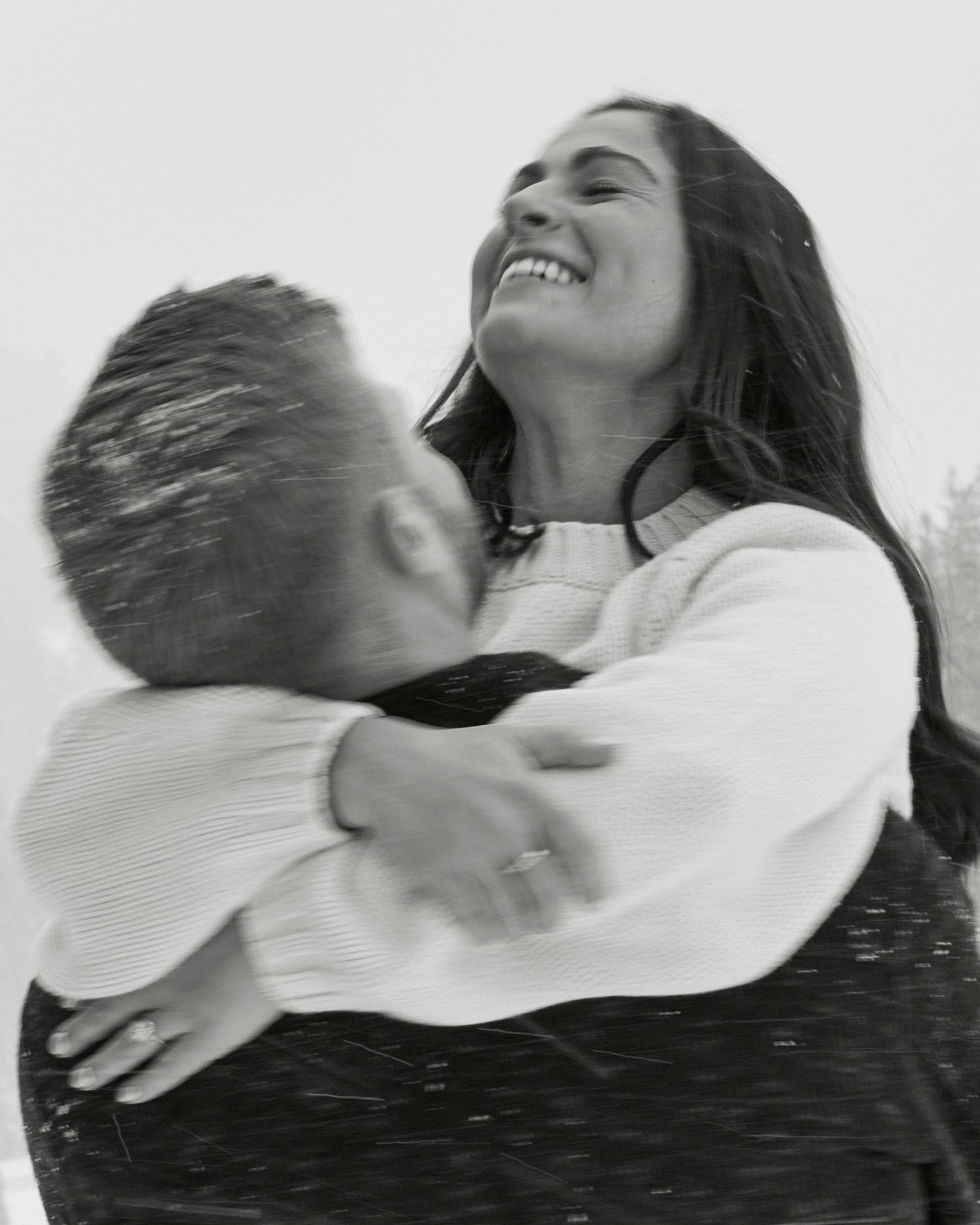 Joyful candid black and white photo of couple embracing and laughing together.