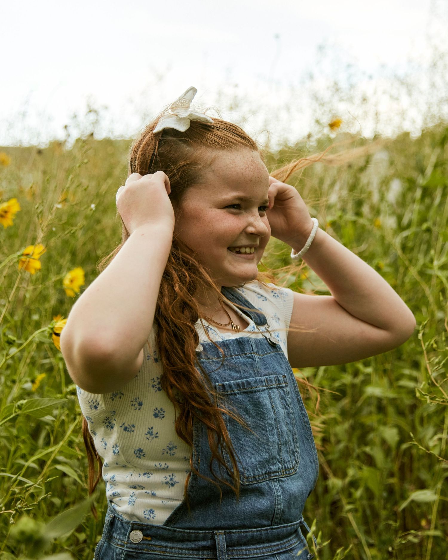 Joyful moment captured in a wildflower meadow wearing denim overalls on a sunny day.