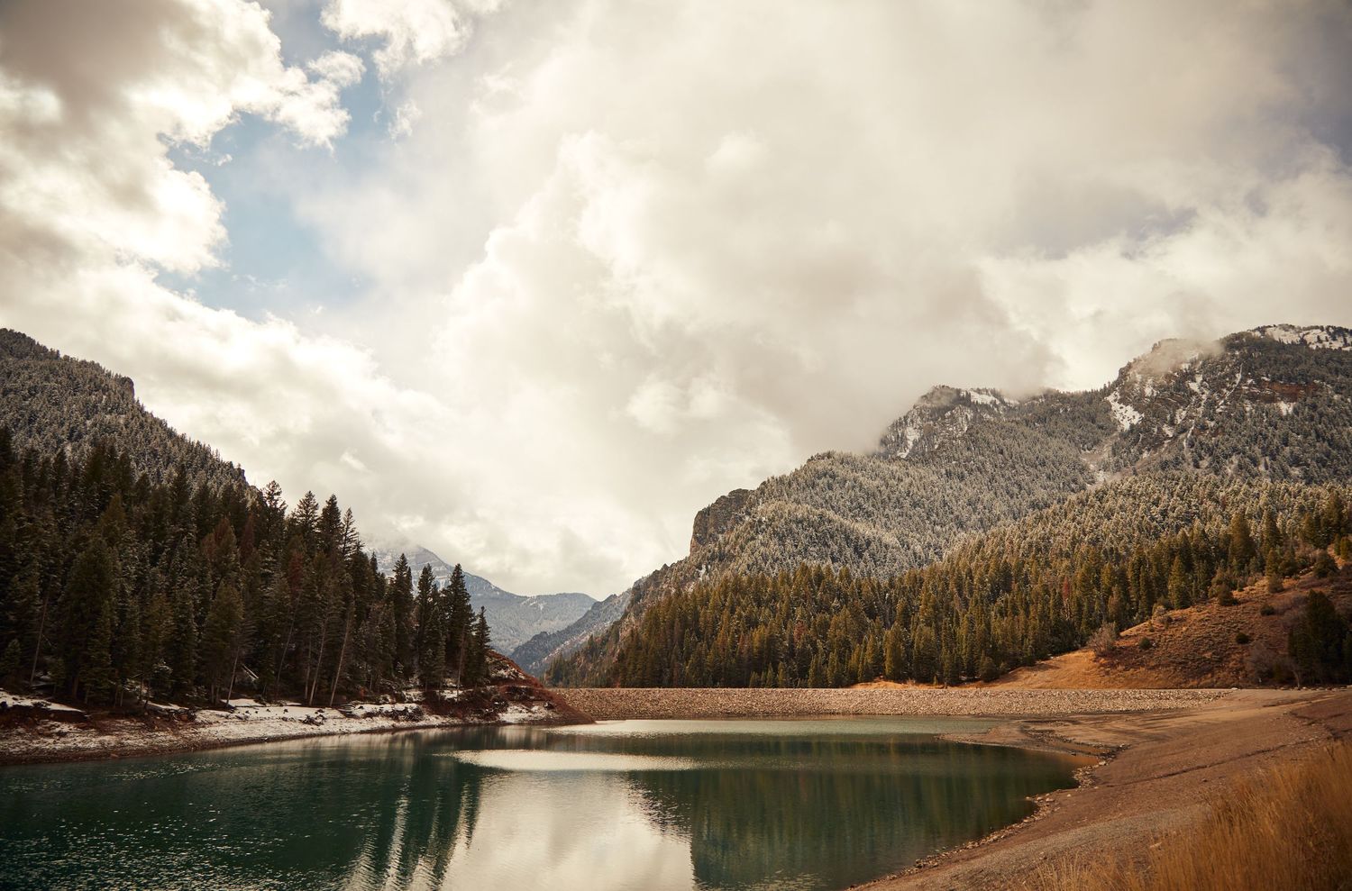 Serene mountain lake surrounded by evergreen forests and towering rocky peaks.