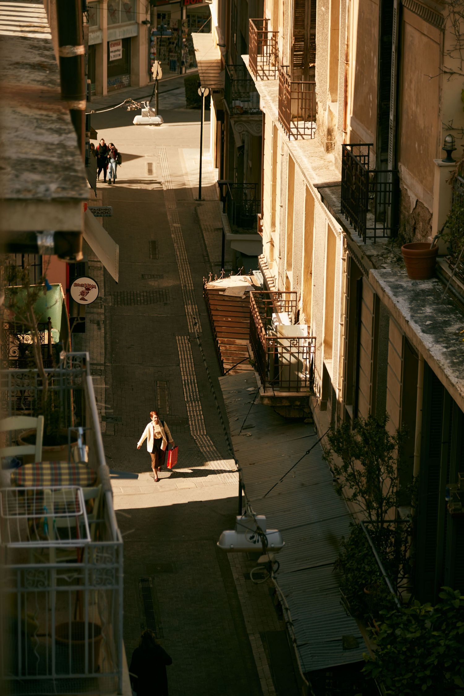 Aerial view of a narrow European street with buildings casting long shadows.