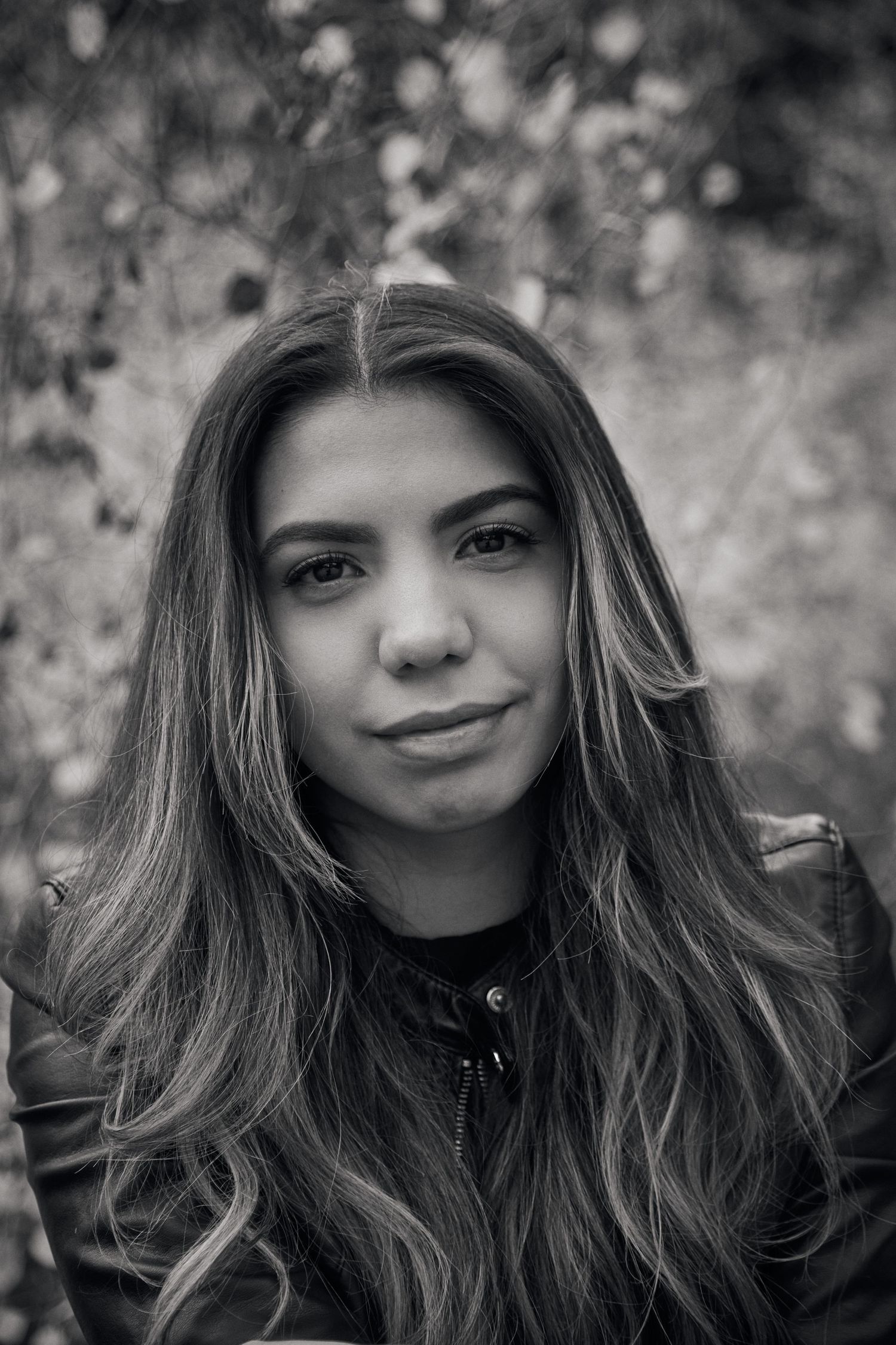 Black and white portrait shot with soft natural lighting and flowing hair against a blurred background.