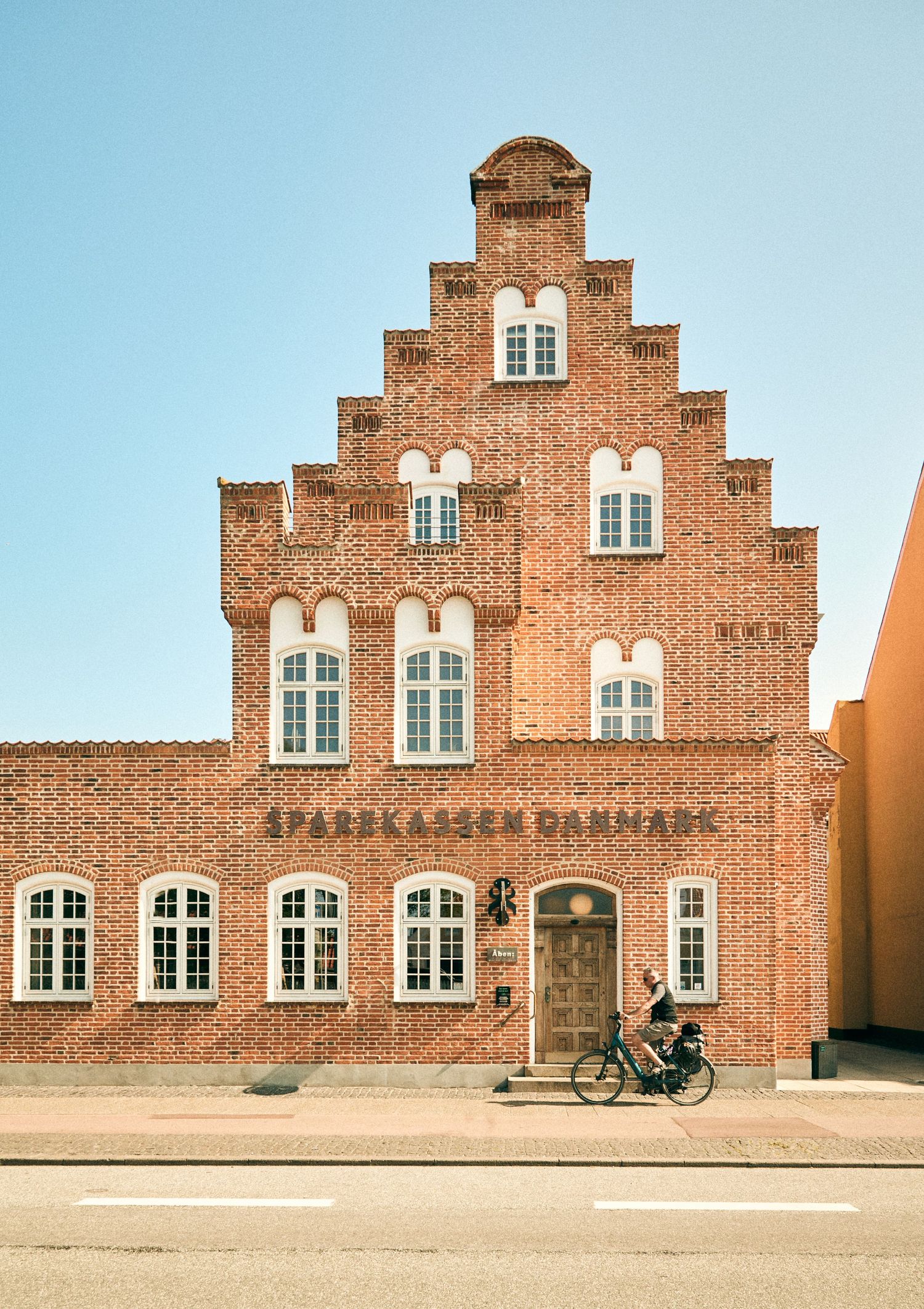 Historic Dutch-style brick building with stepped gable facade and a bicycle parked outside.